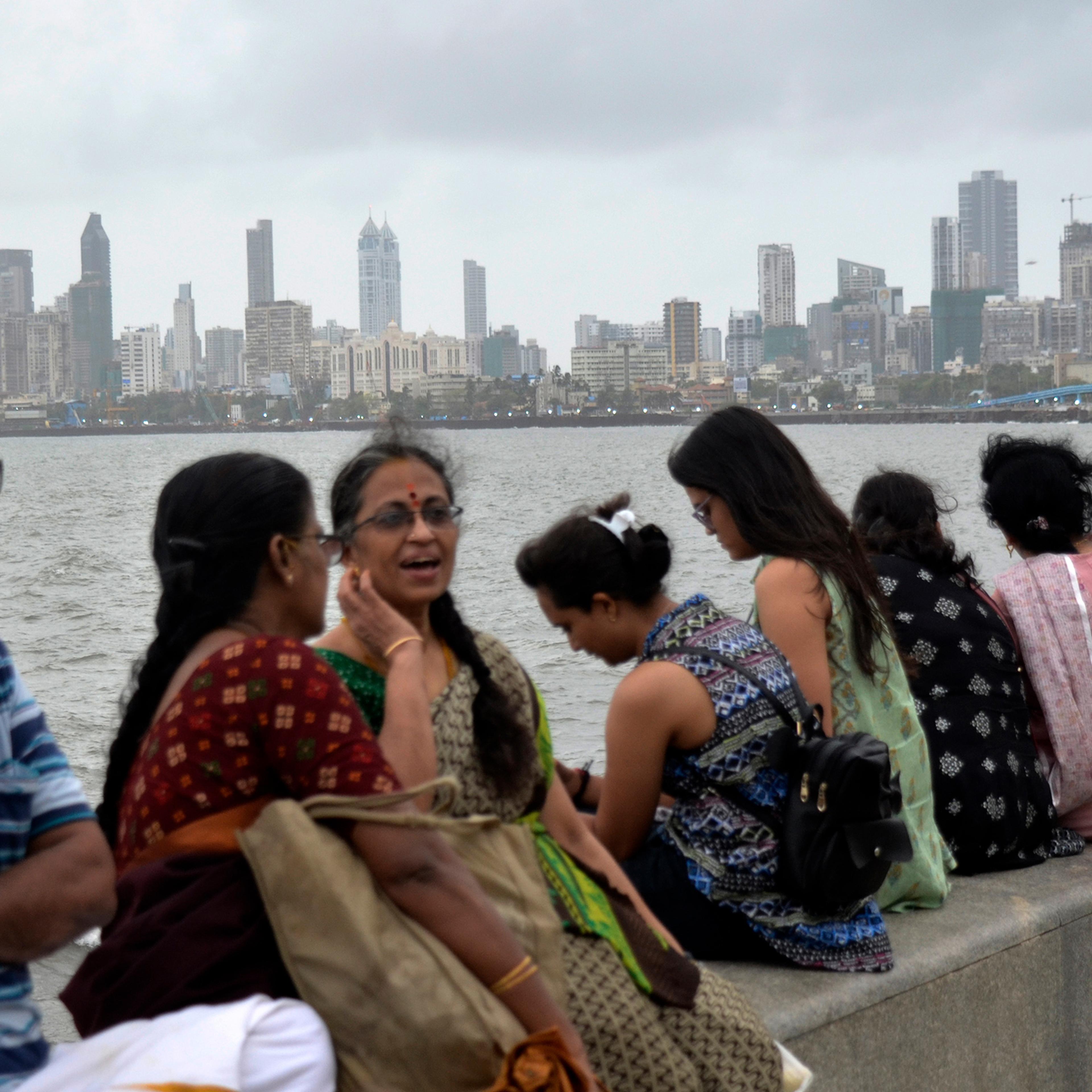 People are seen sitting near marine drive promenade with a cityscape in the background, on the day of World Population Day in Mumbai, India, July 11.