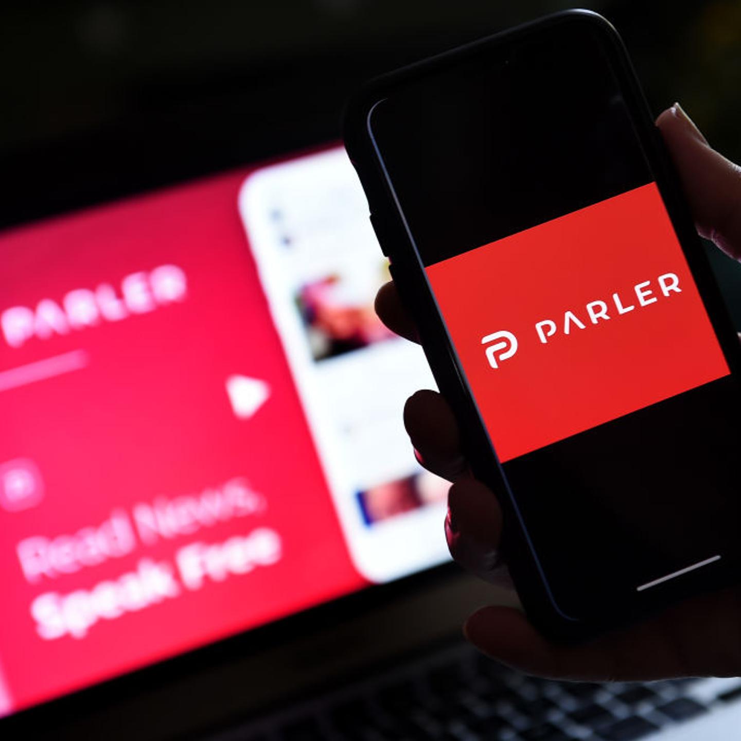 This illustration picture shows social media application logo from Parler displayed on a smartphone with its website in the background