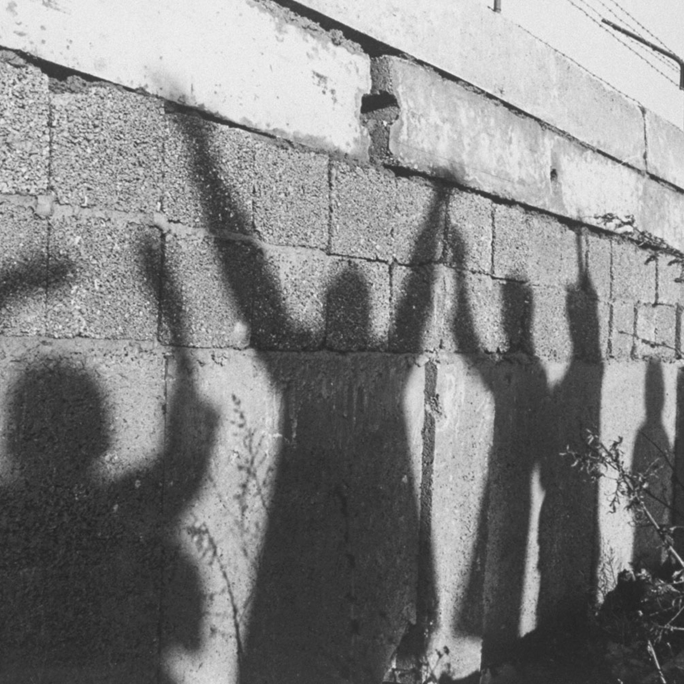 Silhouettes of West Berliners waving to their relatives on the other side are cast across the Berlin Wall.
