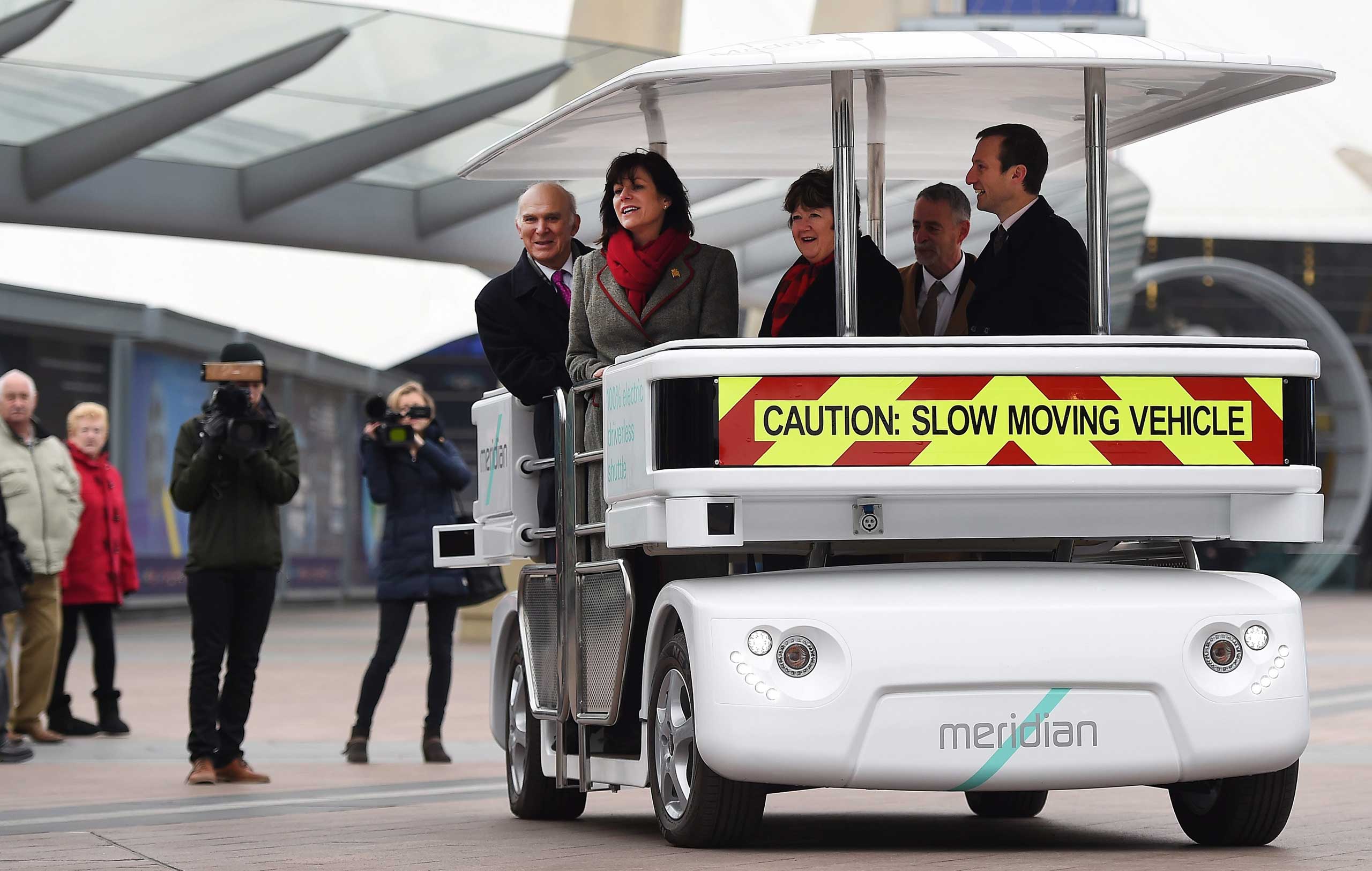 British Transport Minister Claire Perry and British Secretary of State for Business Innovation and Skills Vince Cable ride a driverless 'Meridian' vehicle in London, Feb. 11,2015.