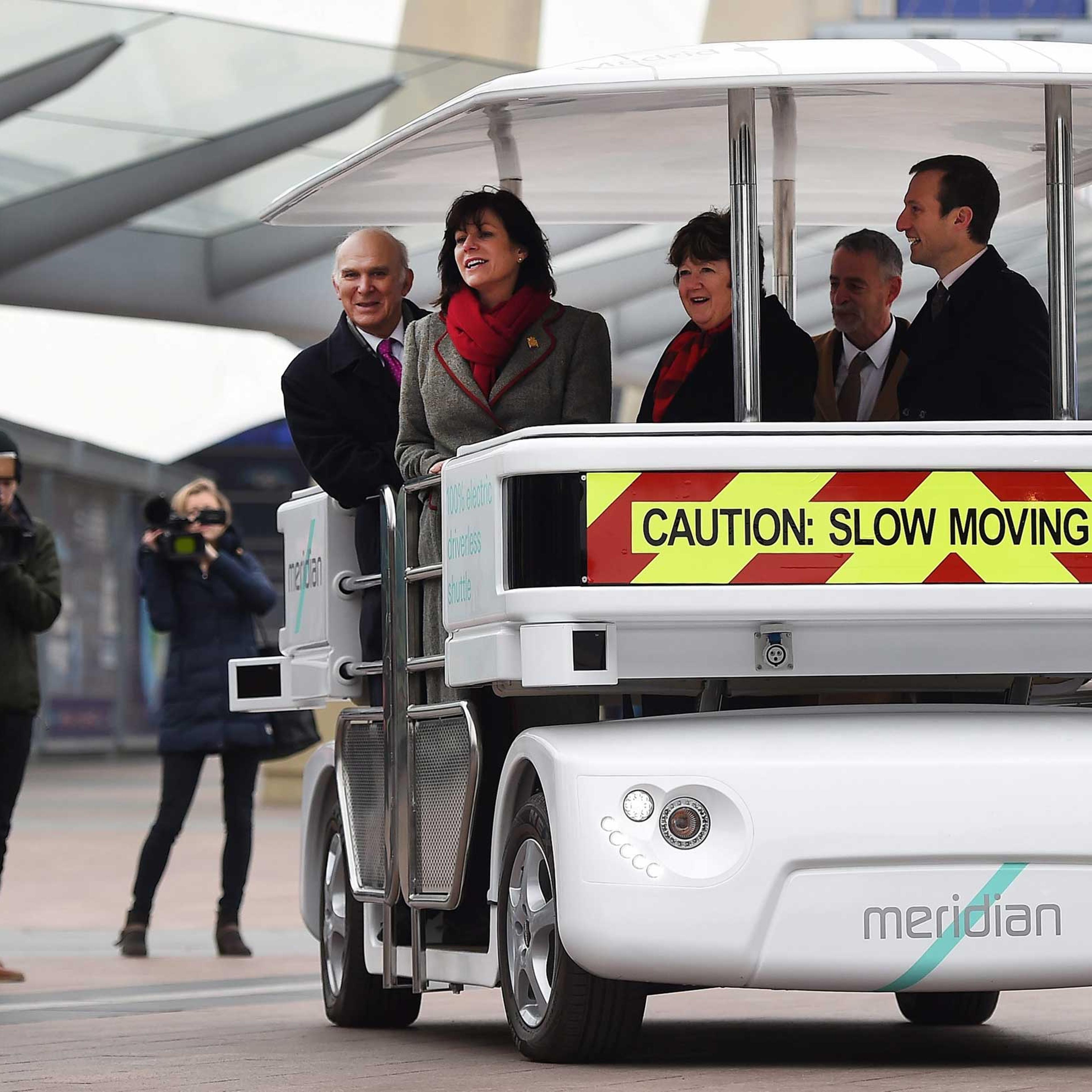 British Transport Minister Claire Perry and British Secretary of State for Business Innovation and Skills Vince Cable ride a driverless 'Meridian' vehicle in London, Feb. 11,2015.
