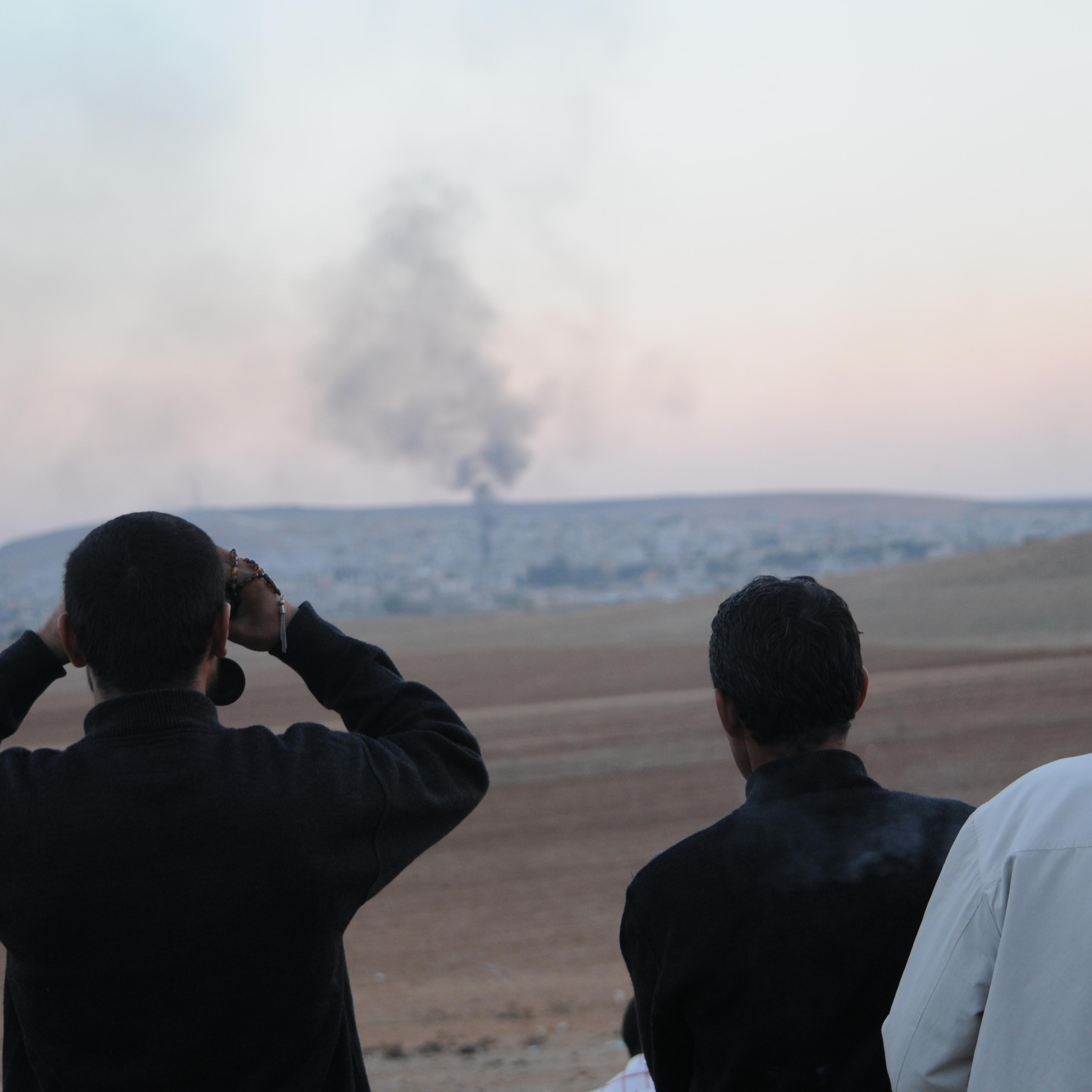 Groups of Kurdish men look at the siege of the Syrian town of Kobane from the Turkish border.