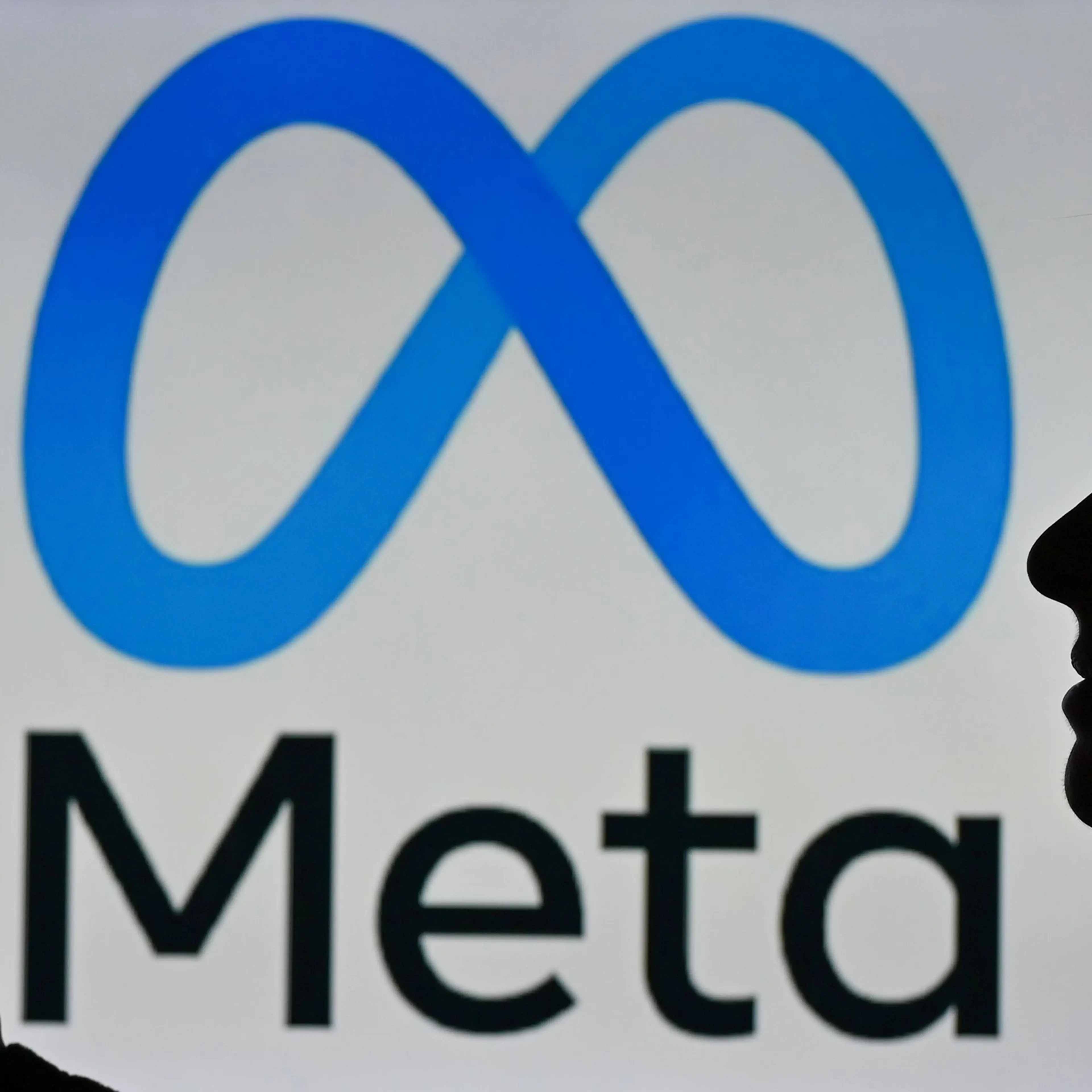 A woman in Edmonton, Canada holds a cell phone in front of a Meta logo, January 2022.