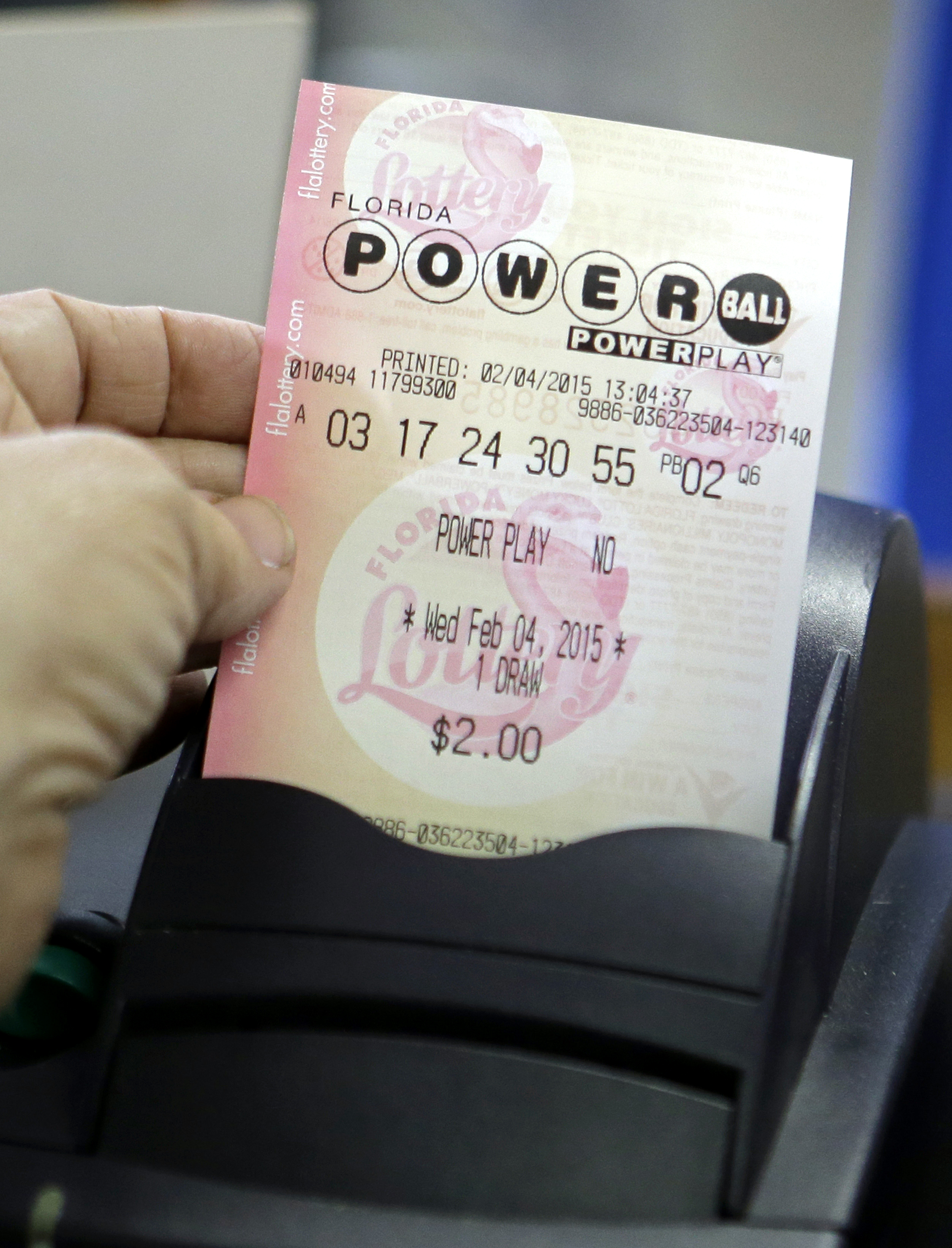 A store clerk pulls a Powerball ticket after being printed for a customer at a local grocery store in Hialeah, Fla. on Feb. 4, 2015.