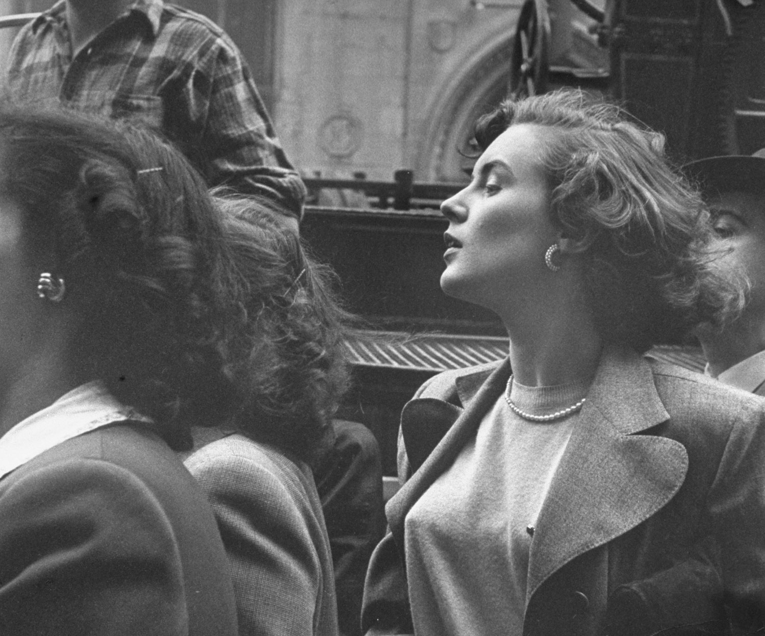 "Gwyned Filling, alone in a crowd that has gathered to watch a fire in the city, stands on tiptoe and tilts back her head to get a better view."