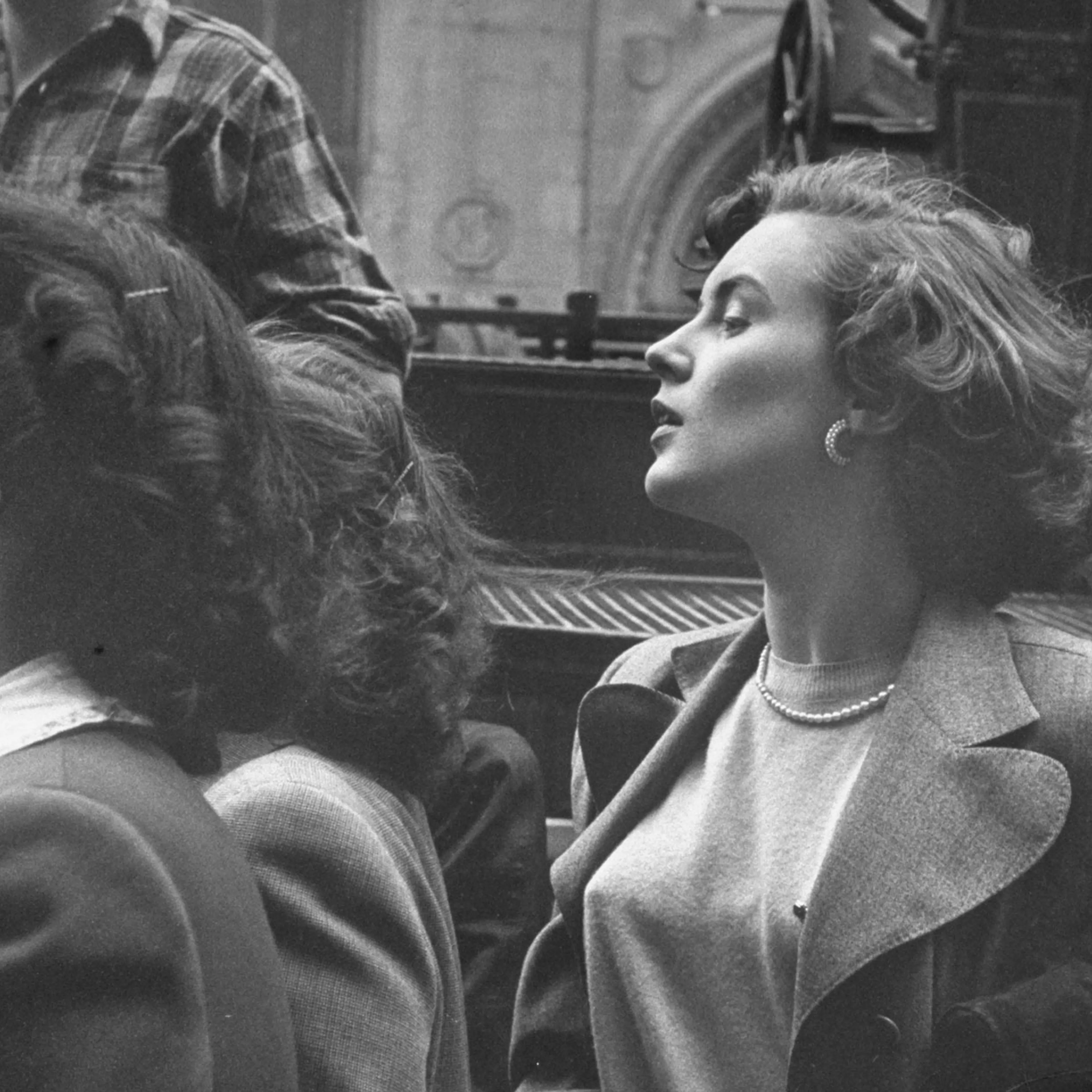 "Gwyned Filling, alone in a crowd that has gathered to watch a fire in the city, stands on tiptoe and tilts back her head to get a better view."