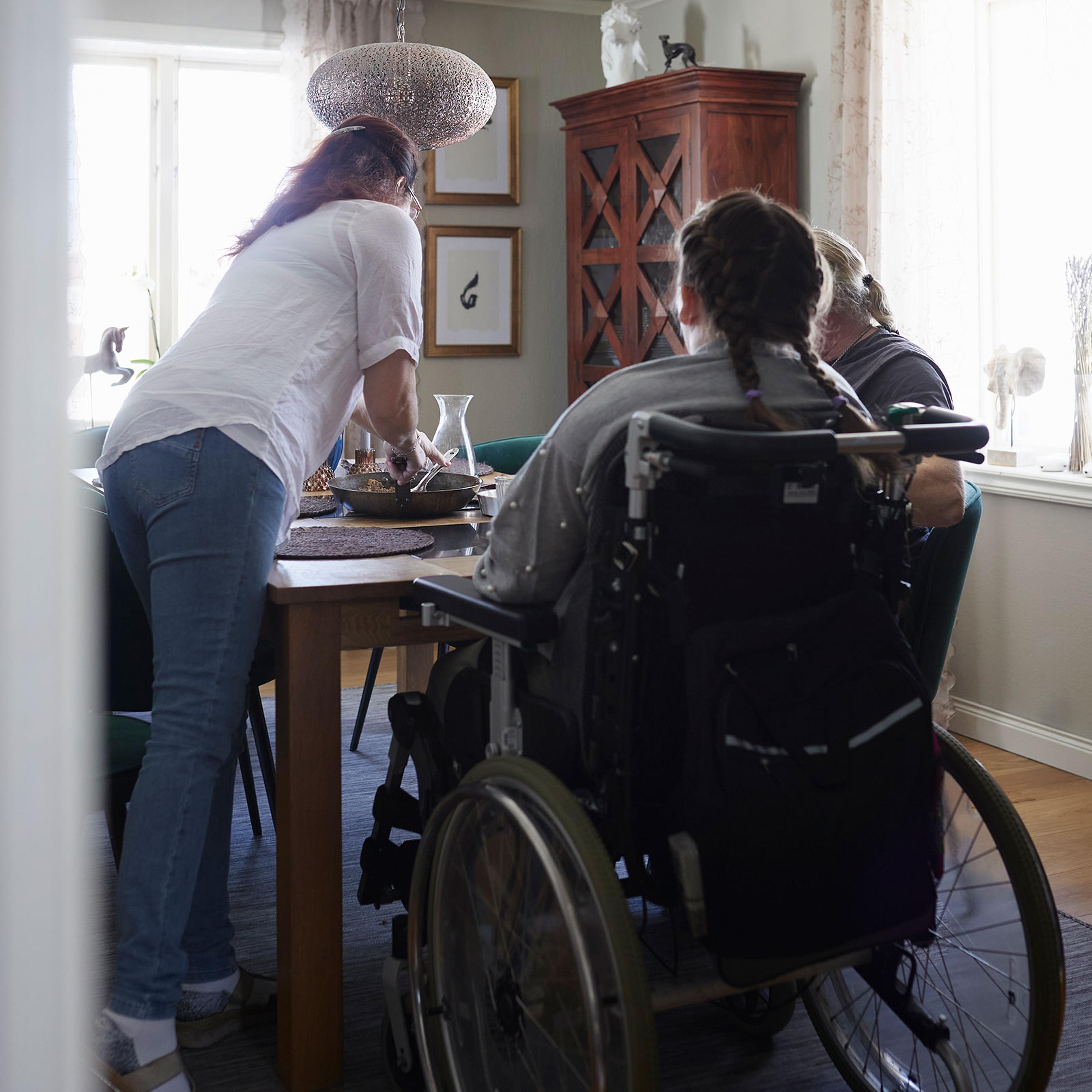 Parents with disabled daughter in wheelchair having meal at dining table