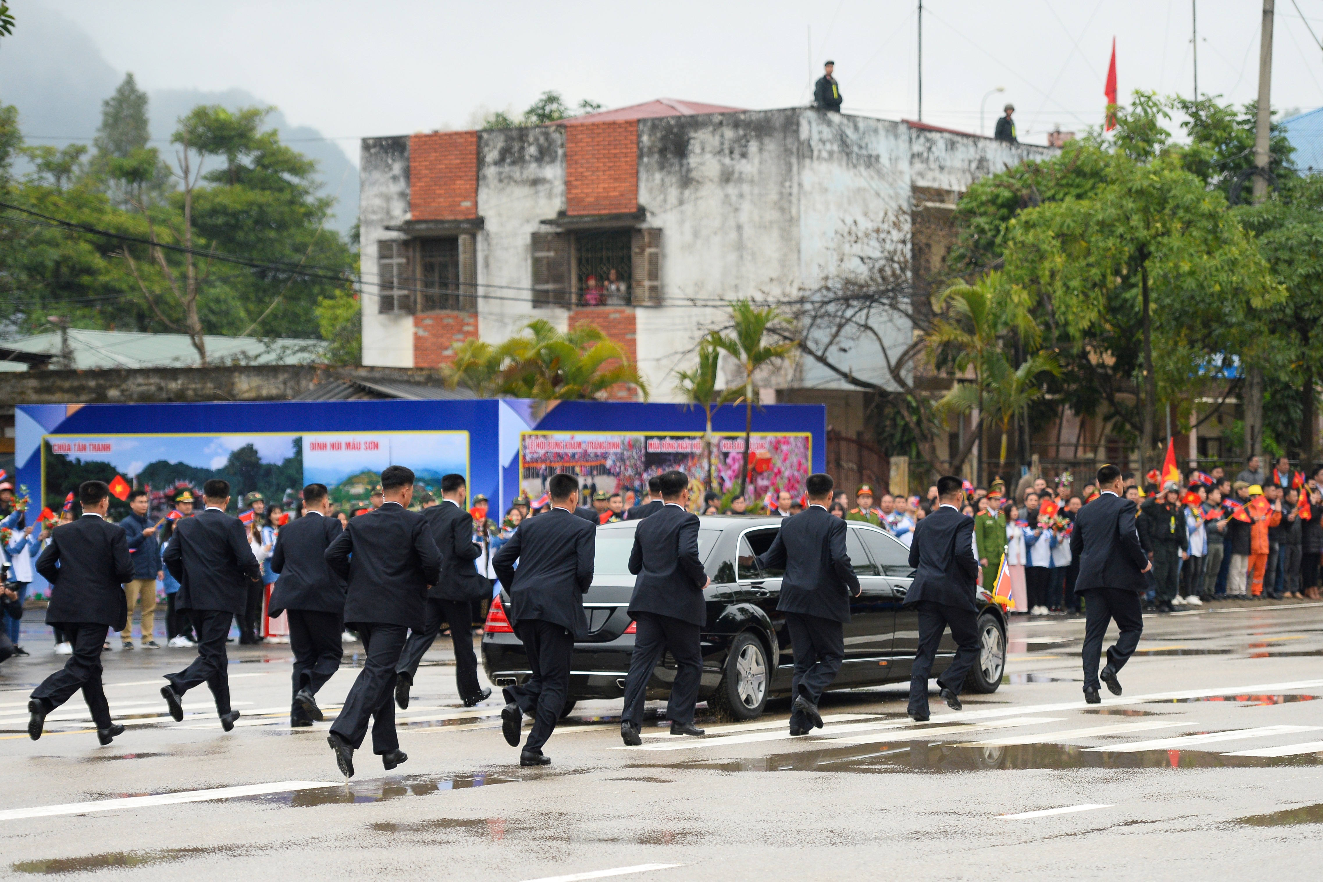 North Korean leader Kim Jong Un's bodyguards run alongside his car as he leaves the Dong Dang railway station for summit