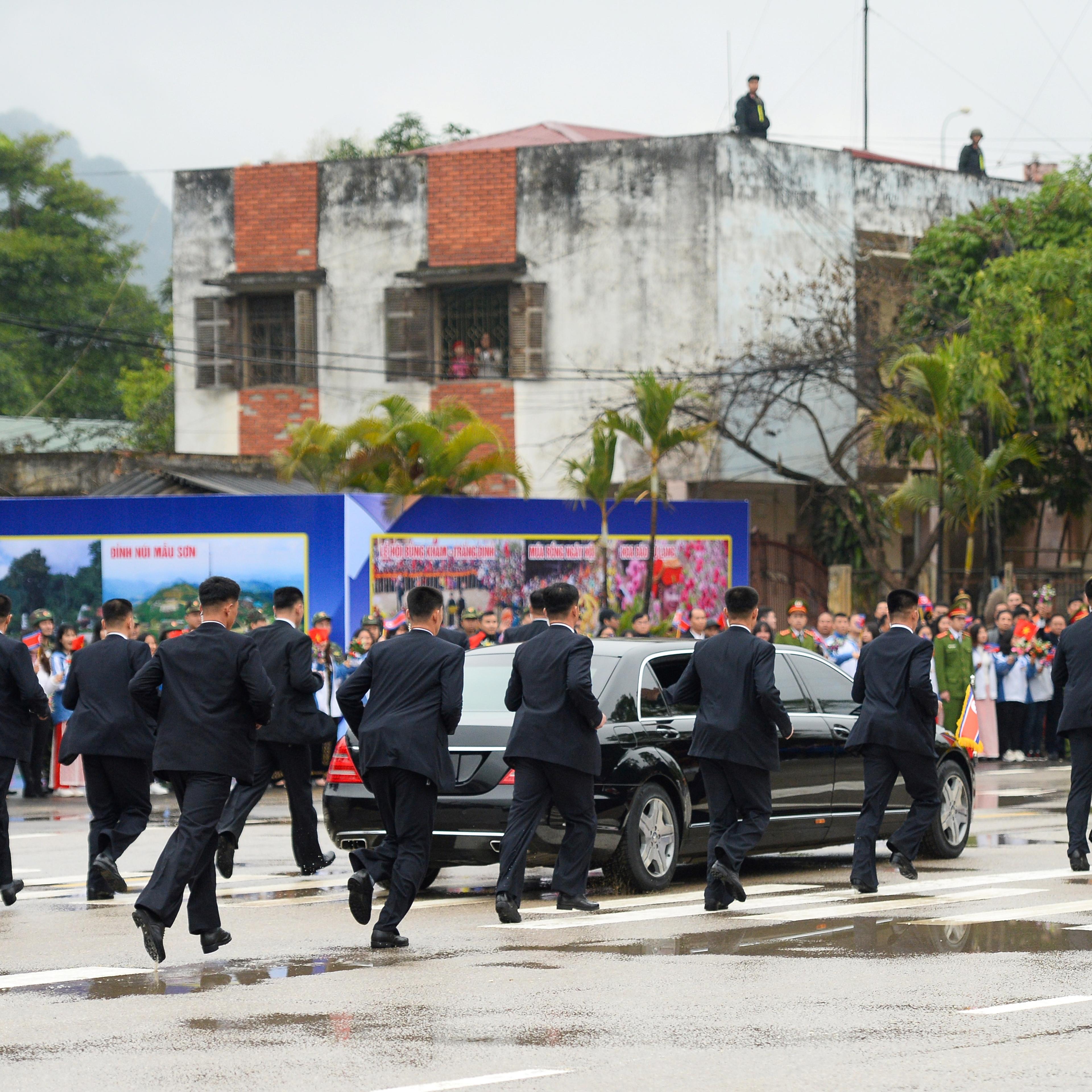 North Korean leader Kim Jong Un's bodyguards run alongside his car as he leaves the Dong Dang railway station for summit
