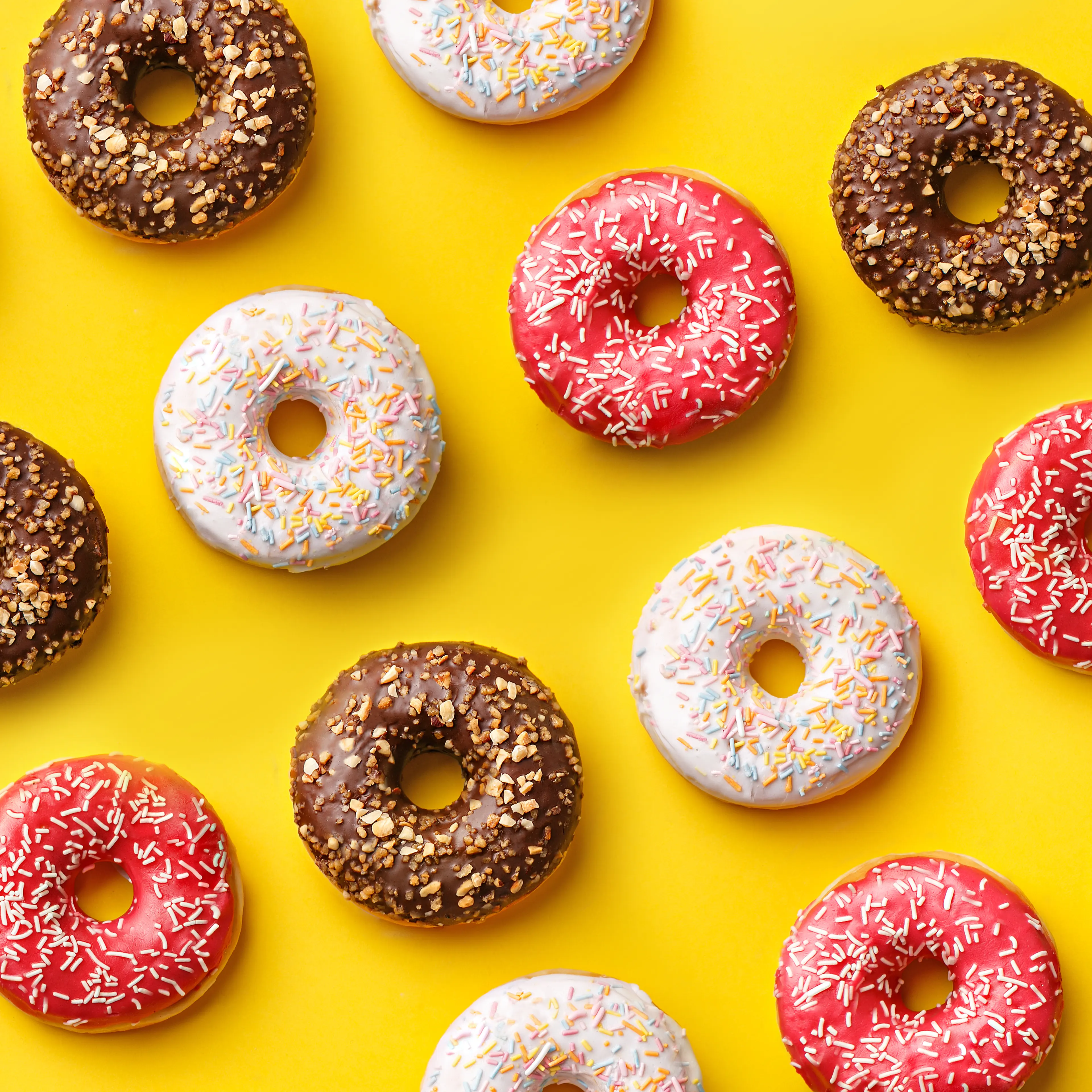 Flat lay donuts pattern on a yellow background. Top view
