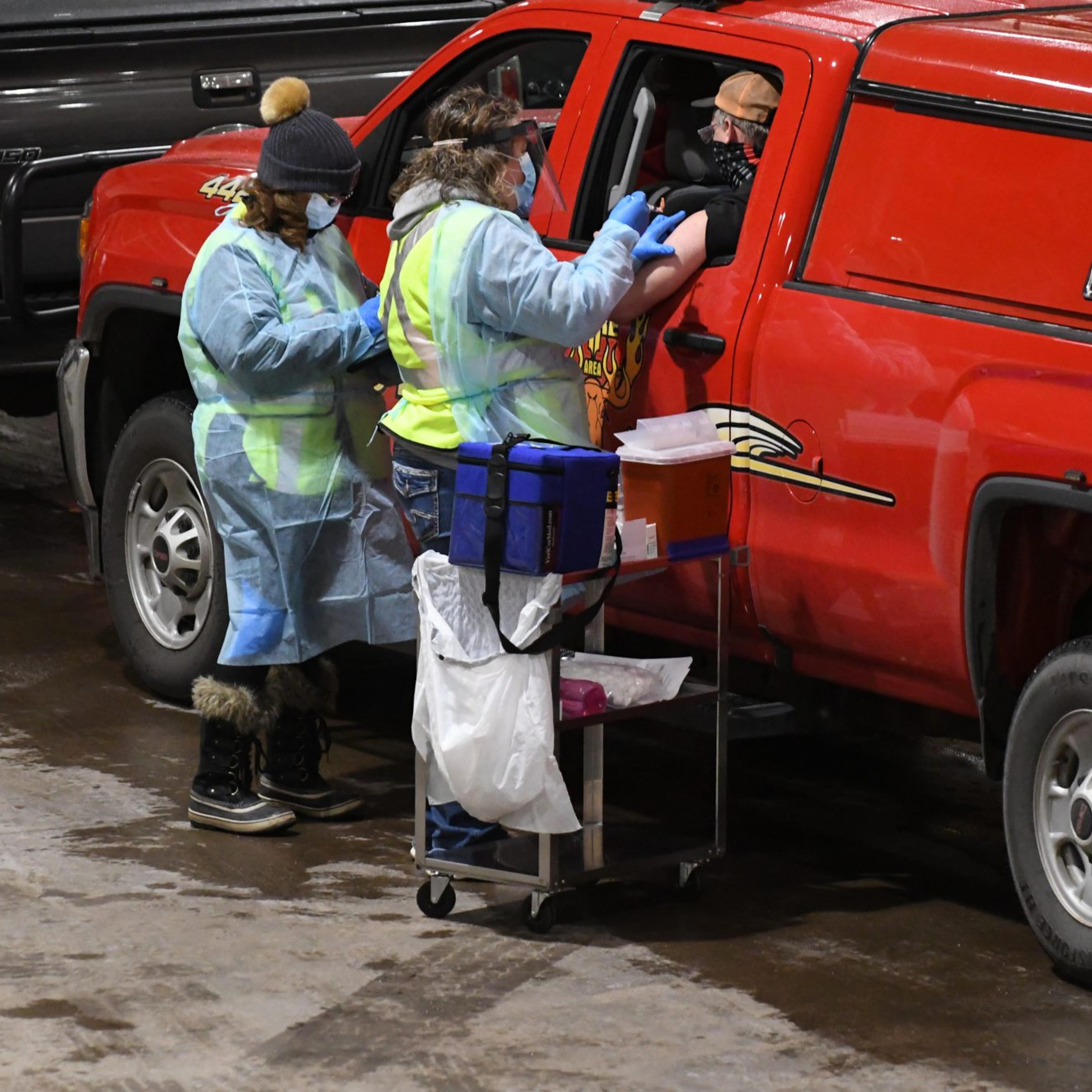 A fire fighter receives a COVID-19 vaccine shot on day one of Carlton County's drive-through vaccination clinic