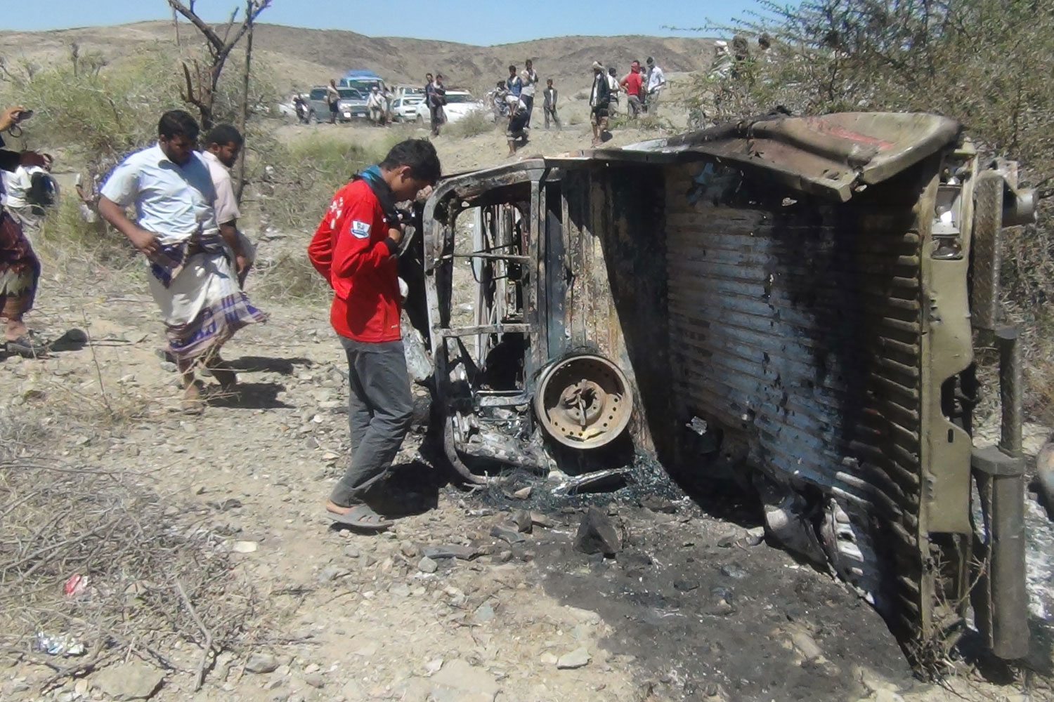 People inspect the wreckage of a car hit by an air strike in the central Yemeni province of al-Bayda on April 19, 2014. 