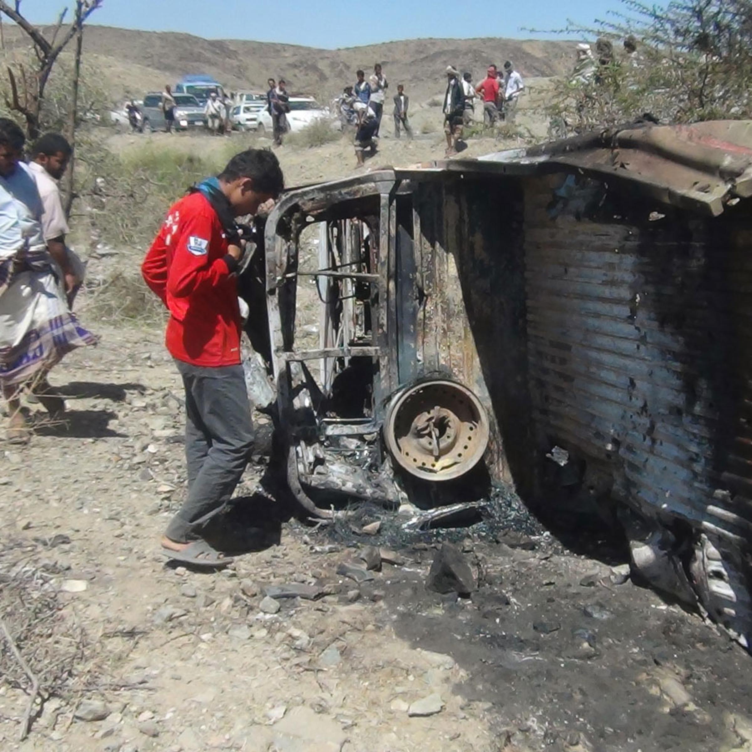 People inspect the wreckage of a car hit by an air strike in the central Yemeni province of al-Bayda on April 19, 2014.