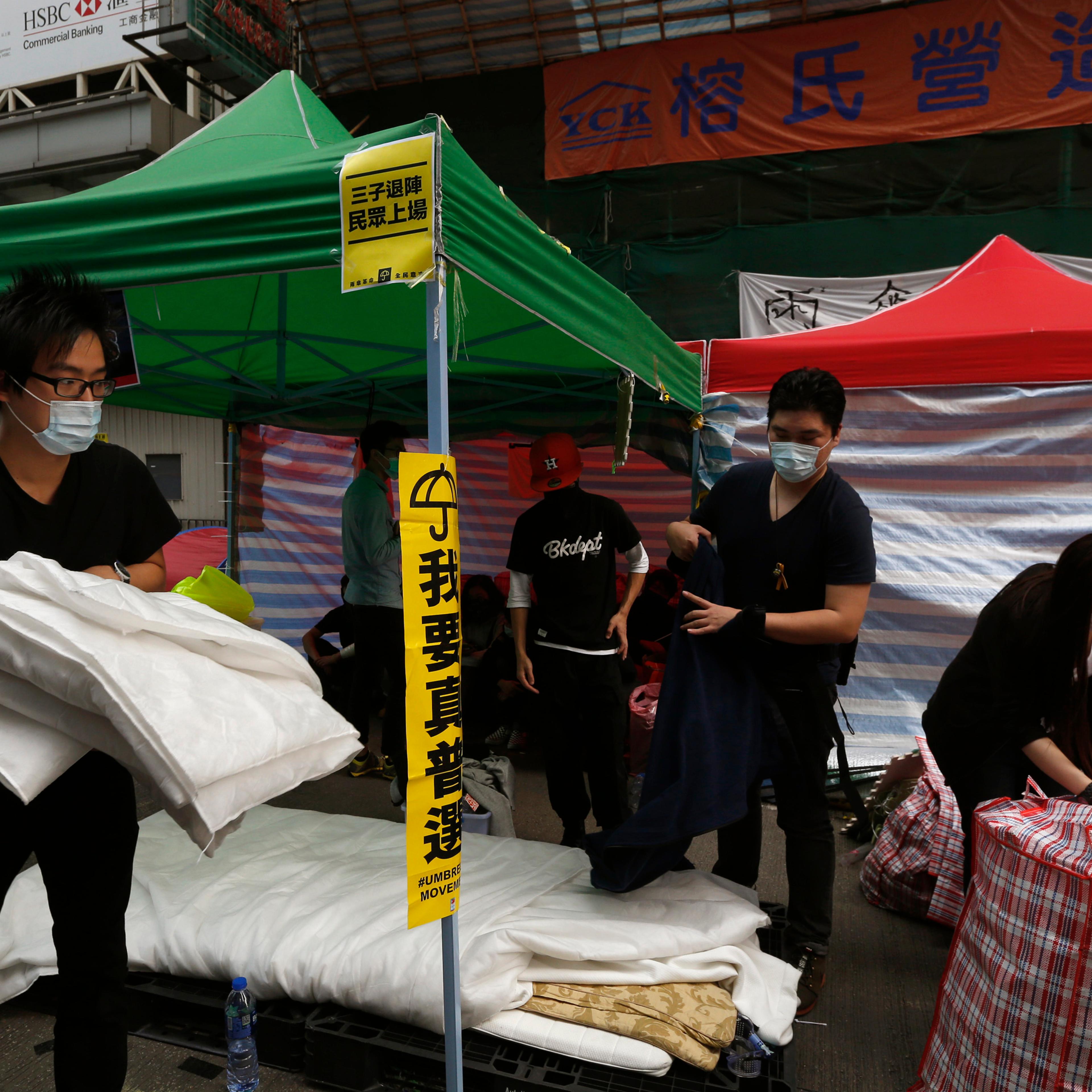Masked pro-democracy protesters pack their belongings, before they are removed by bailiffs under a court injunction, at Mong Kok shopping district in Hong Kong