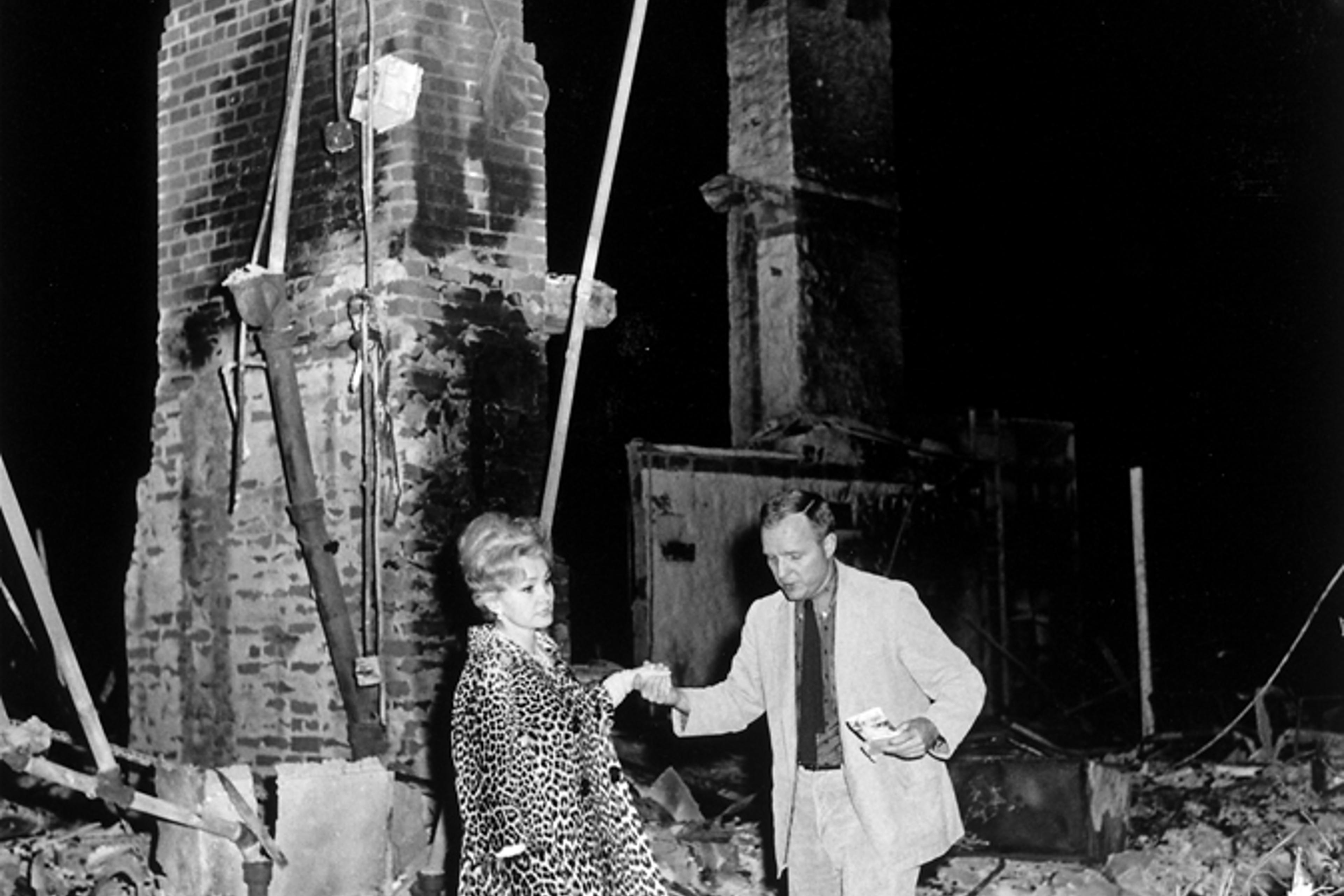 LIFE magazine editor Richard Stolley helps Zsa Zsa Gabor through the remains of her Bel Air, Calif., home, destroyed by fire in November 1961.