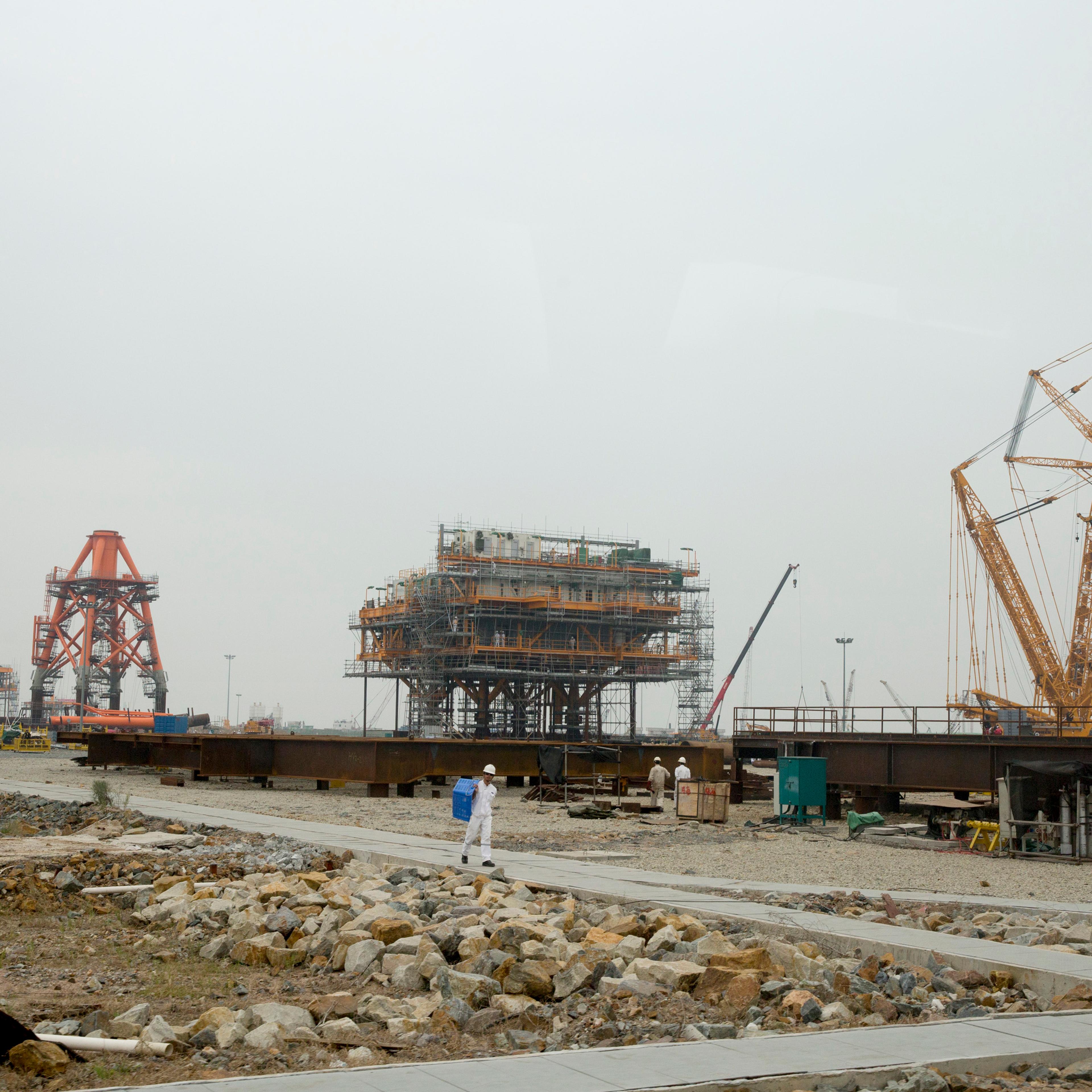Cranes stand on a drilling platform construction site at the yard of Offshore Oil Engineering Co., a unit of CNOOC Ltd., in the Zhuhai Gaolan Port Economic Zone in Zhuhai, Guangdong province, China on Nov. 13, 2014.