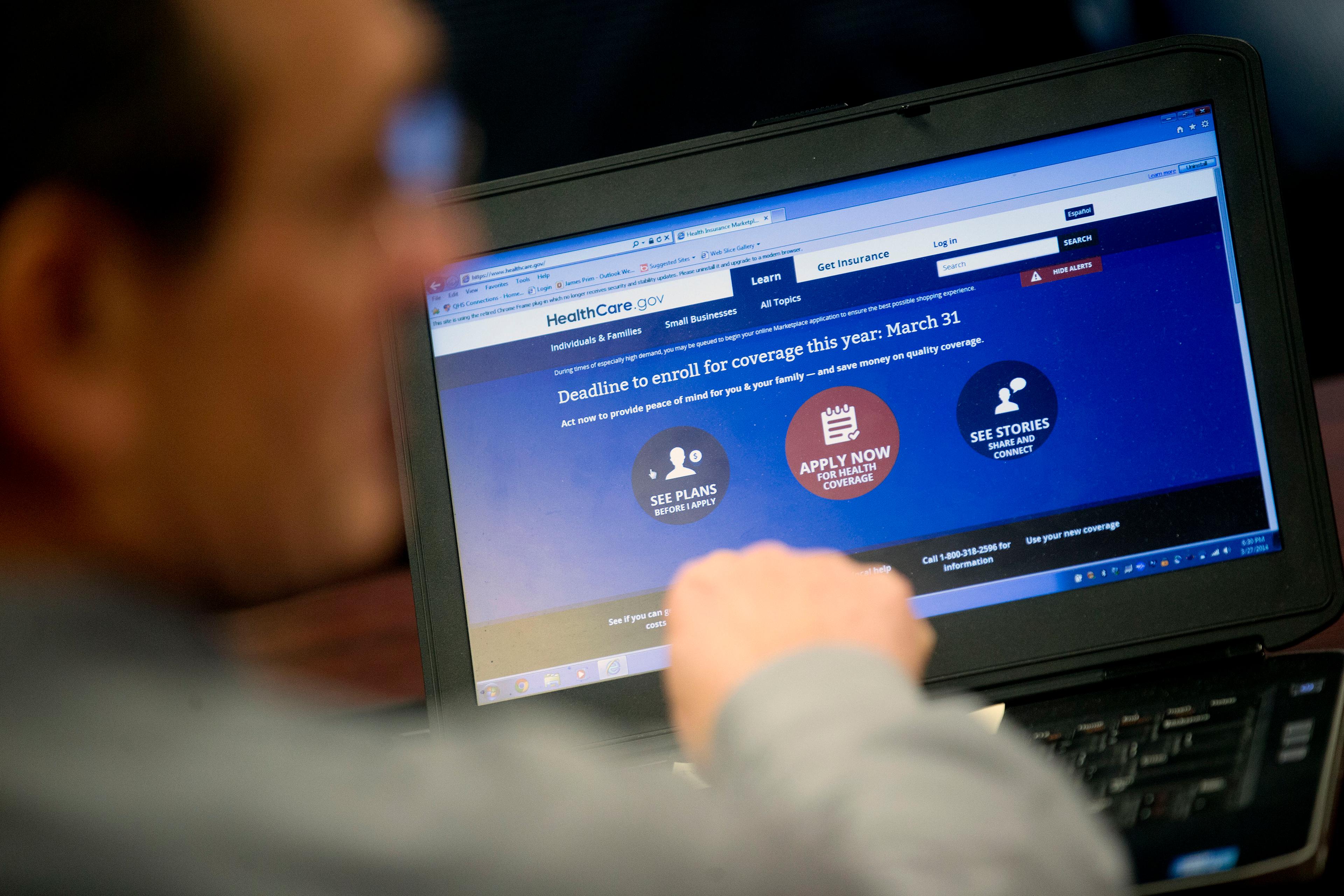 Marketplace guide Jim Prim works on the Healthcare.gov federal enrollment website as he helps a resident sign up for a health insurance plan under the Affordable Care Act at an enrollment event in Milford, Delaware on March 27, 2014.