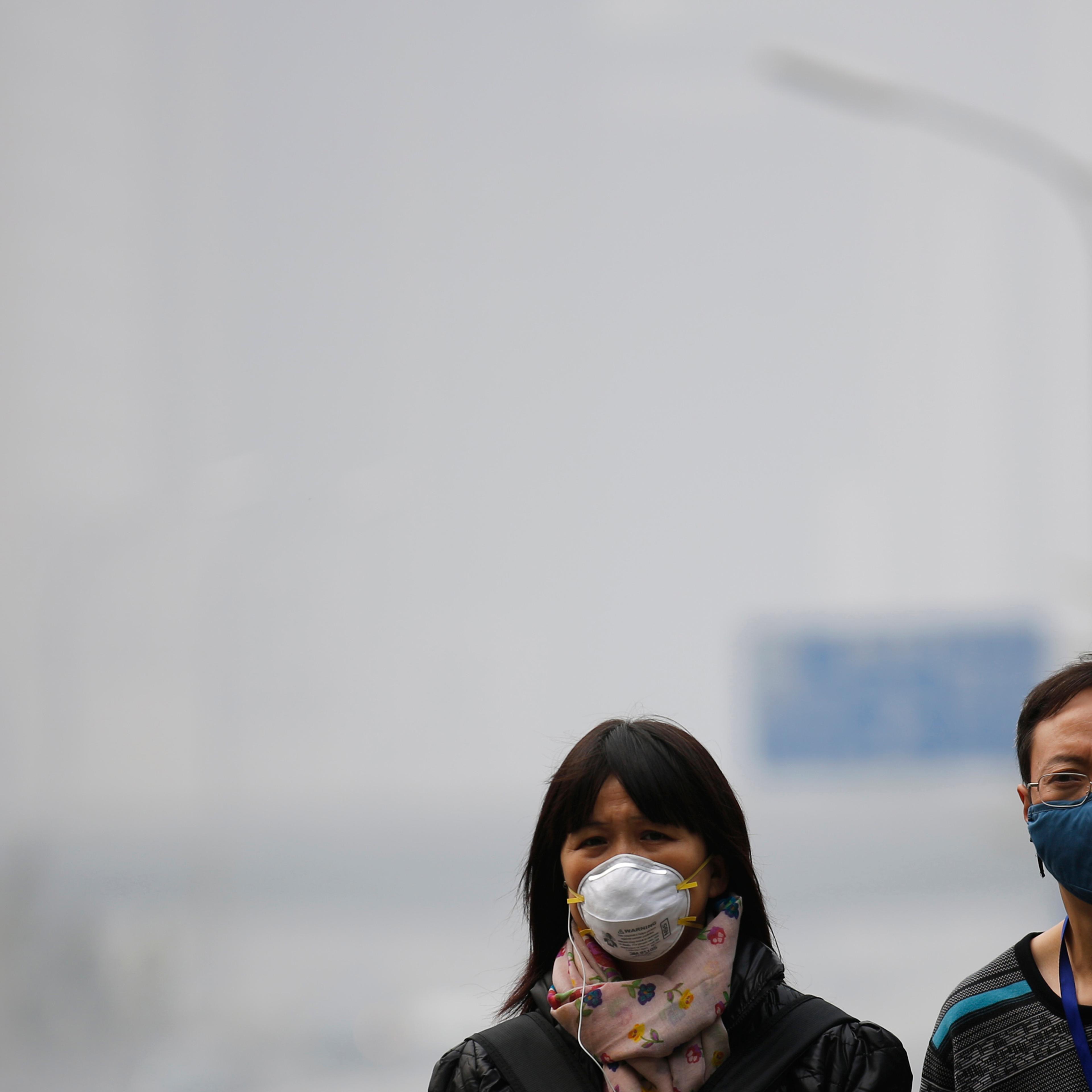 People wearing masks walk on a street amid heavy haze and smog in Beijing