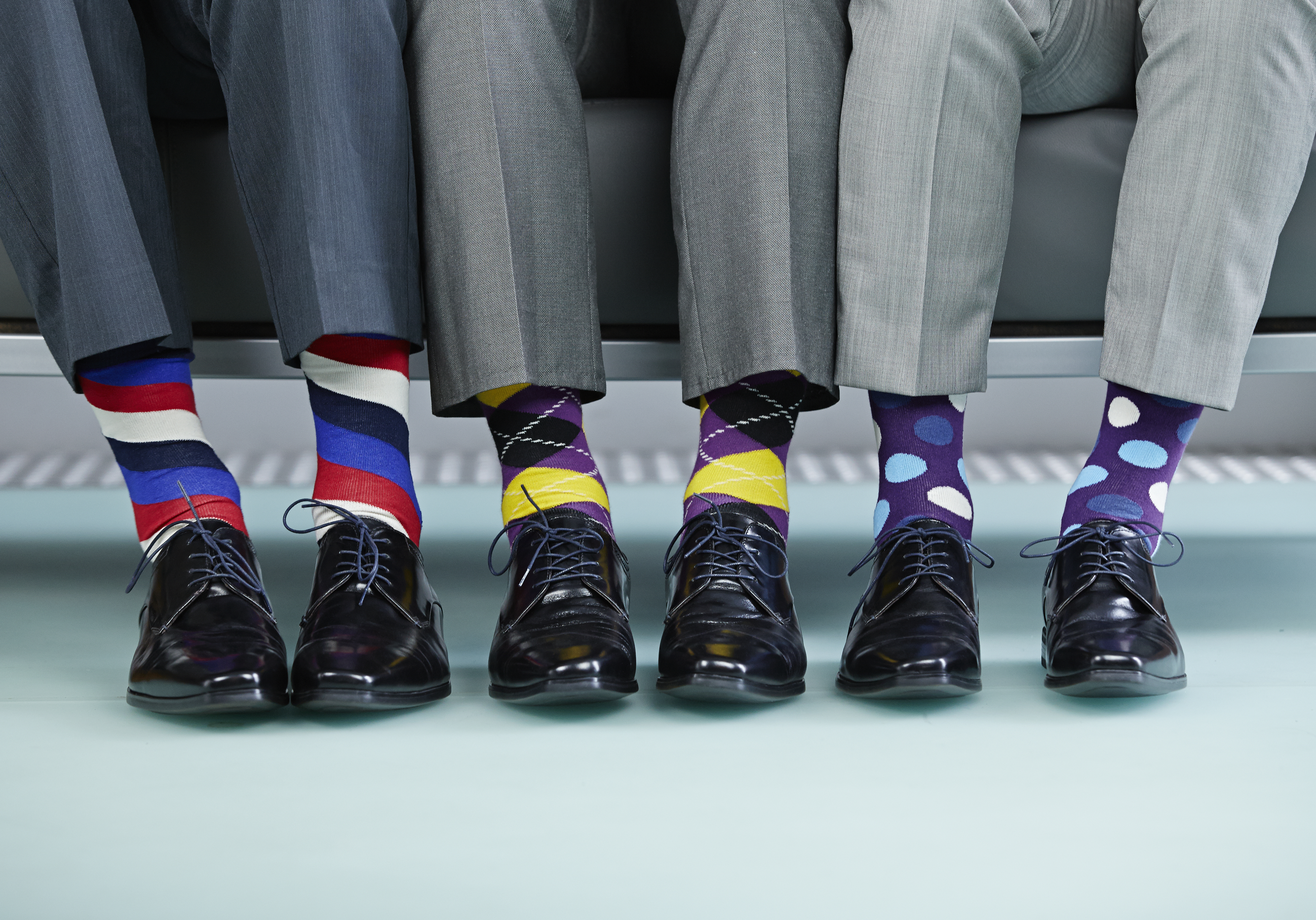 Men sitting on bench wearing colourful socks