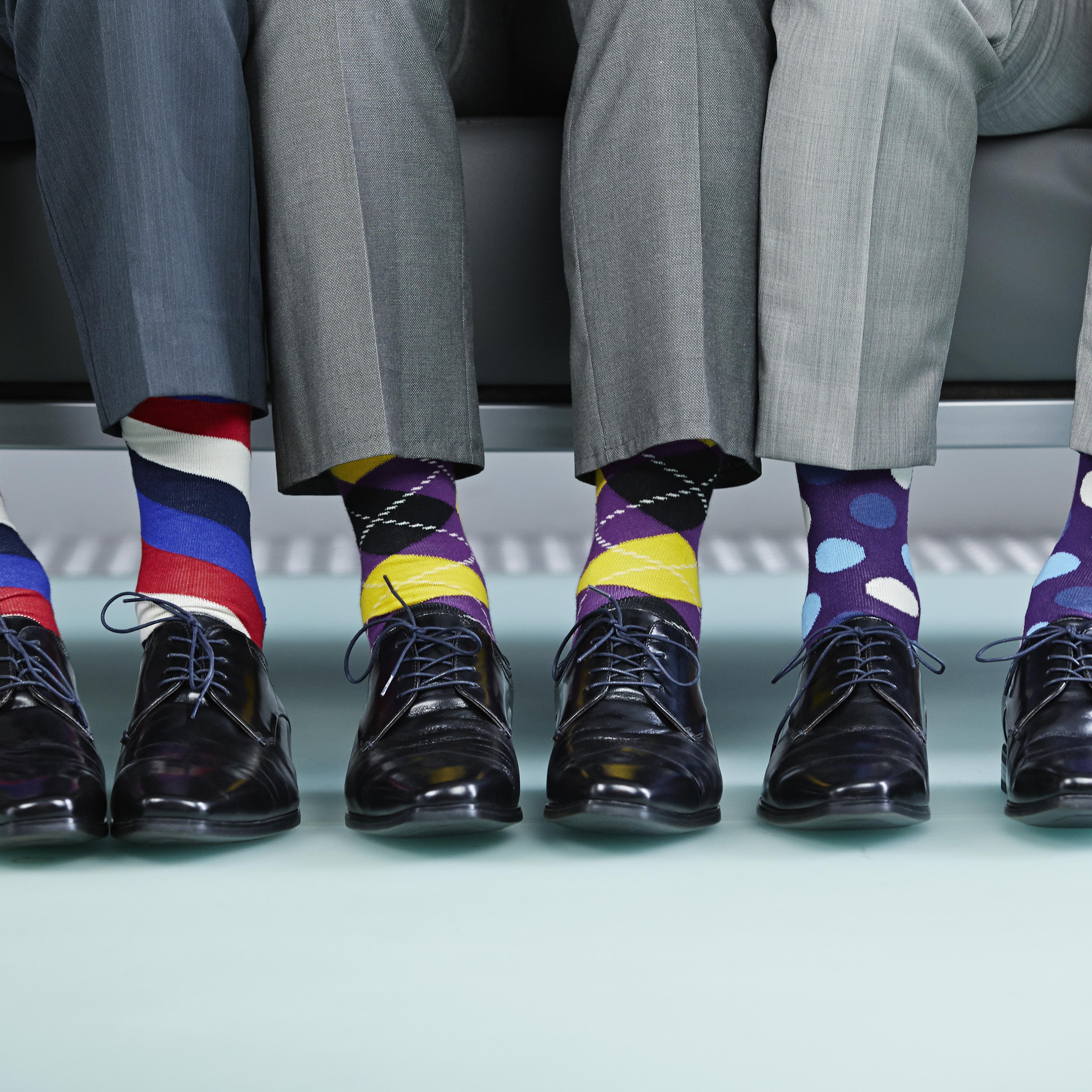 Men sitting on bench wearing colourful socks