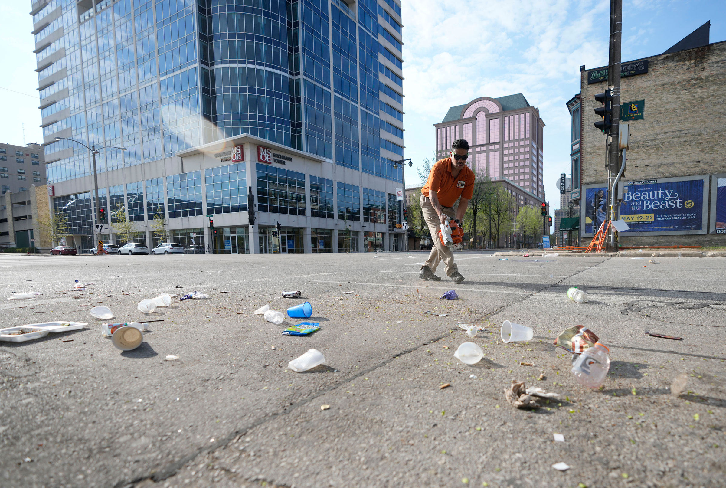 Victor Prado, with MKE Downtown, clears debris near the corner of North Water Street and East Juneau Avenue in Milwaukee, where multiple people were shot and injured late Friday in Milwaukee's downtown bar district after the Milwaukee Bucks playoff game,