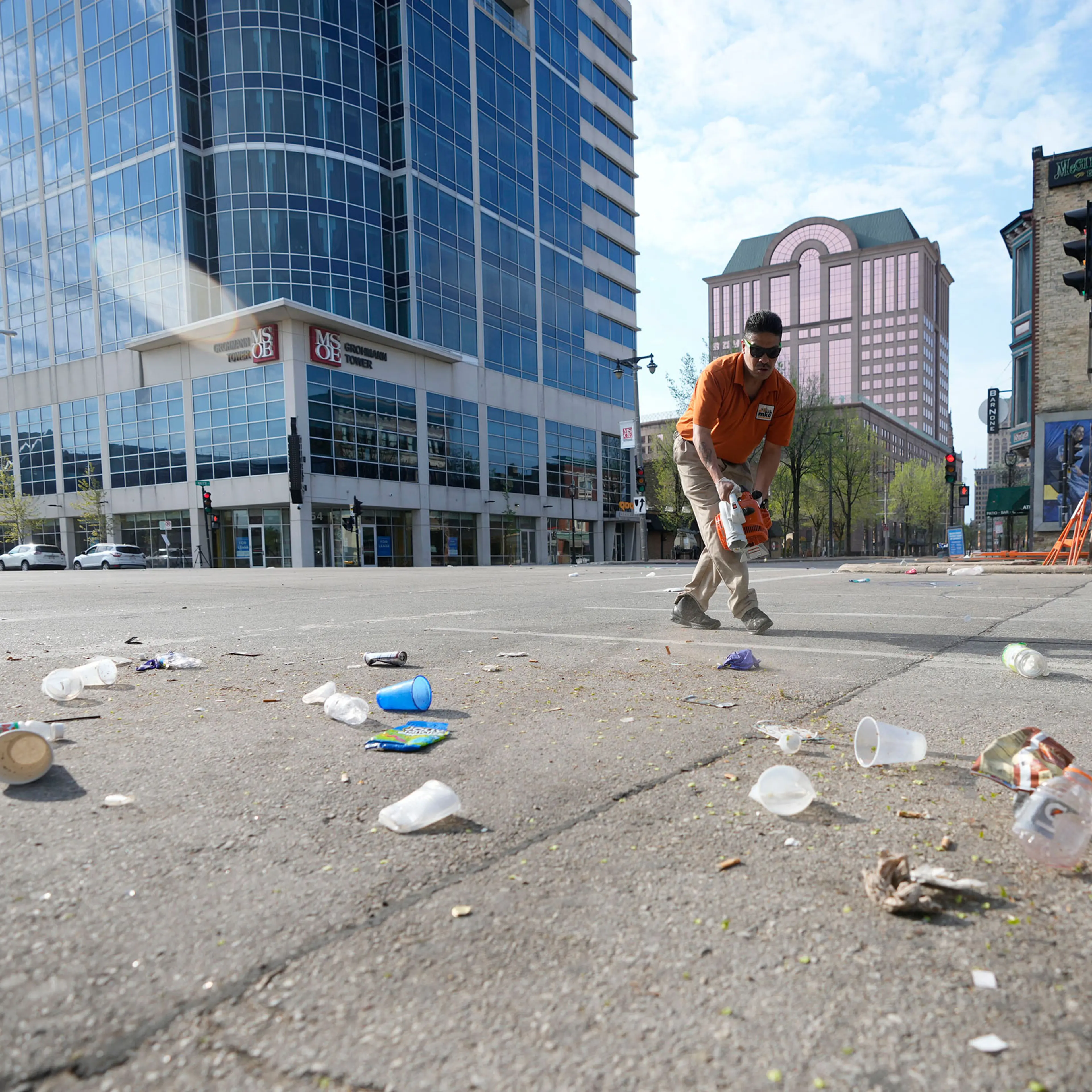 Victor Prado, with MKE Downtown, clears debris near the corner of North Water Street and East Juneau Avenue in Milwaukee, where multiple people were shot and injured late Friday in Milwaukee's downtown bar district after the Milwaukee Bucks playoff game,
