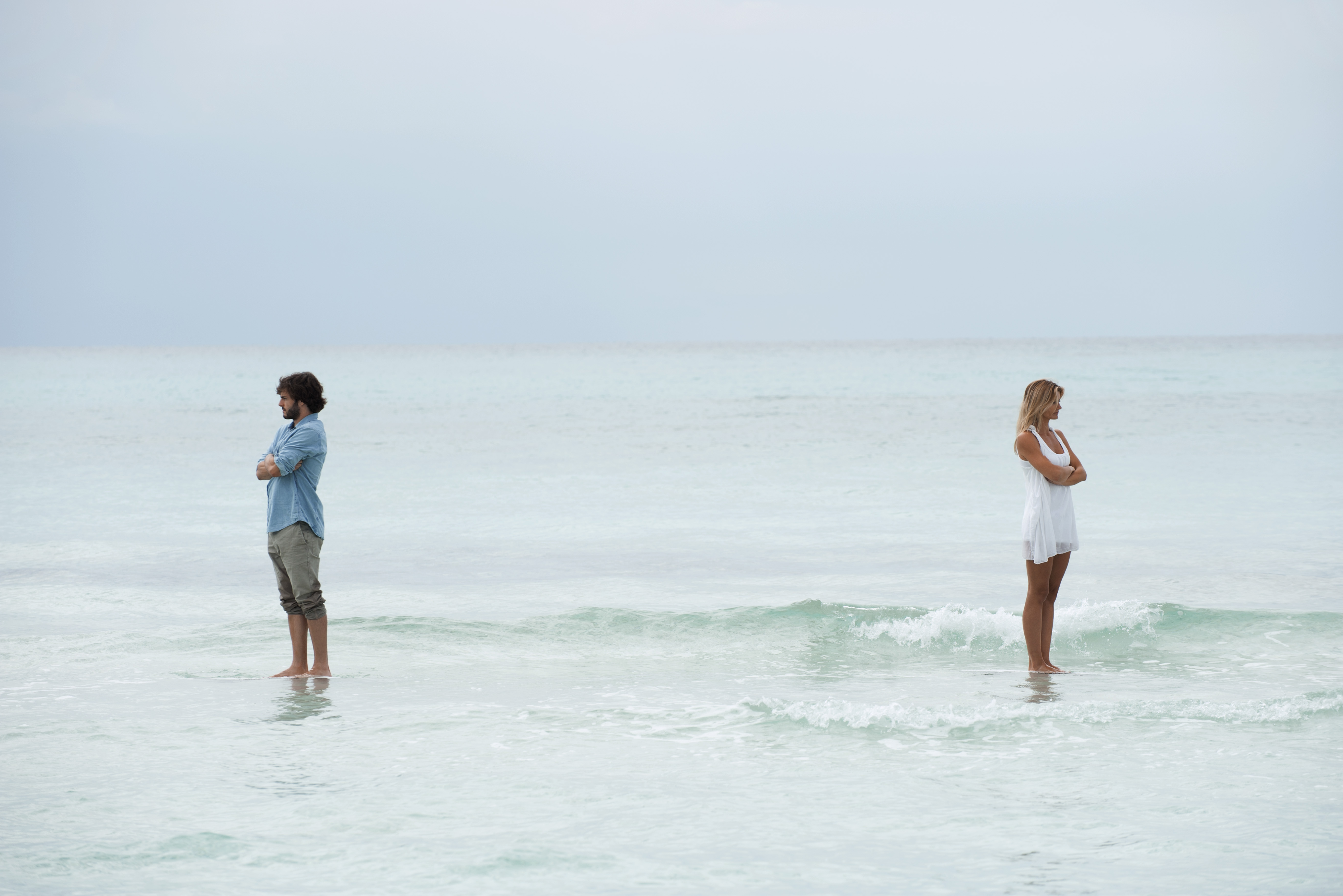 Couple standing apart in sea with backs turned toward each other