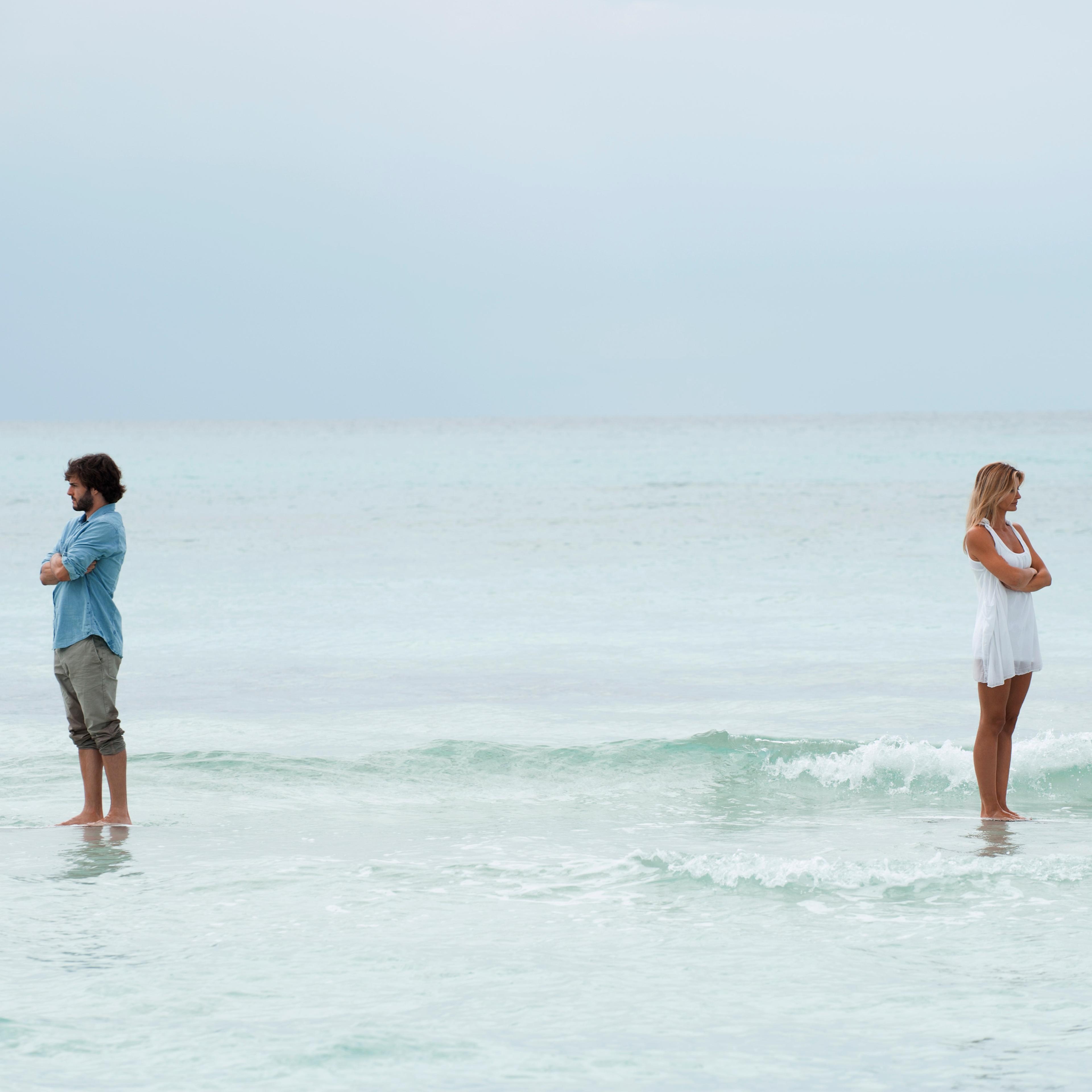 Couple standing apart in sea with backs turned toward each other