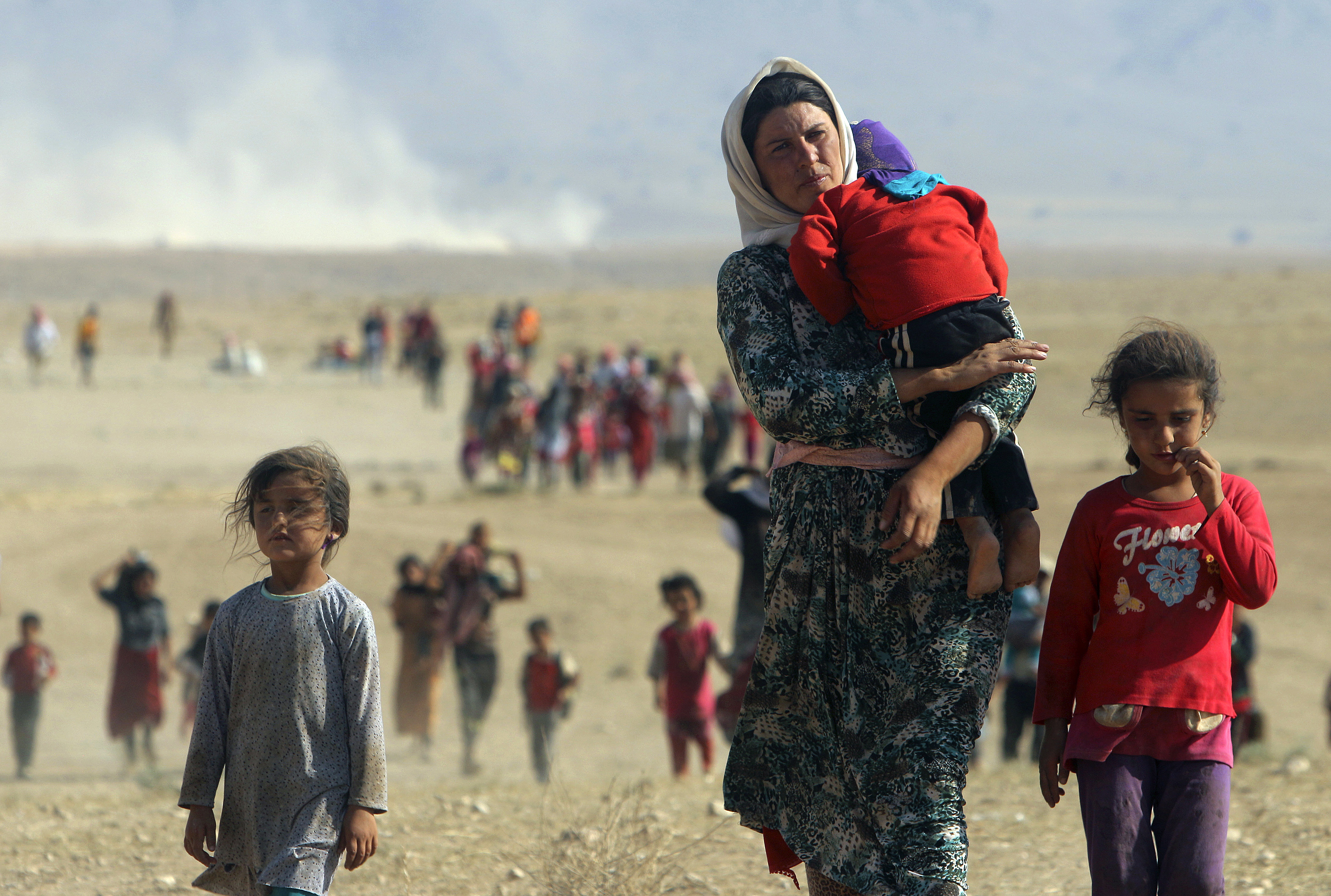 Displaced people from the minority Yazidi sect, fleeing violence from forces loyal to the Islamic State in Sinjar town, walk towards the Syrian border