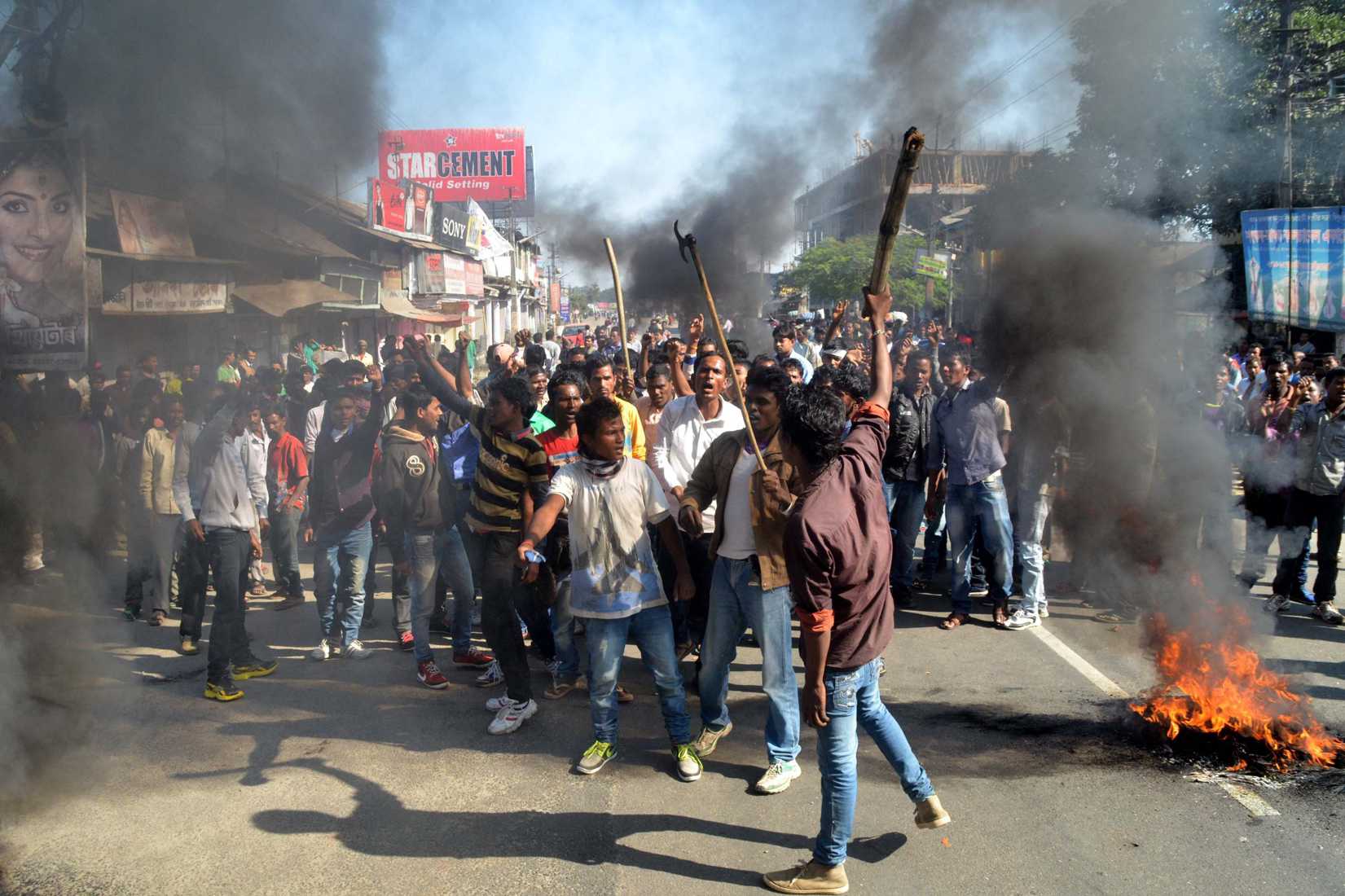 Activists of the Assam Tea Tribes Student Association (ATTSA) shout slogans as they block the road with burning tyres during a protest against attacks on villagers by militants in four different locations, at Biswanath Chariali in the Sonitpur district of northeastern Assam state on December 24, 2014