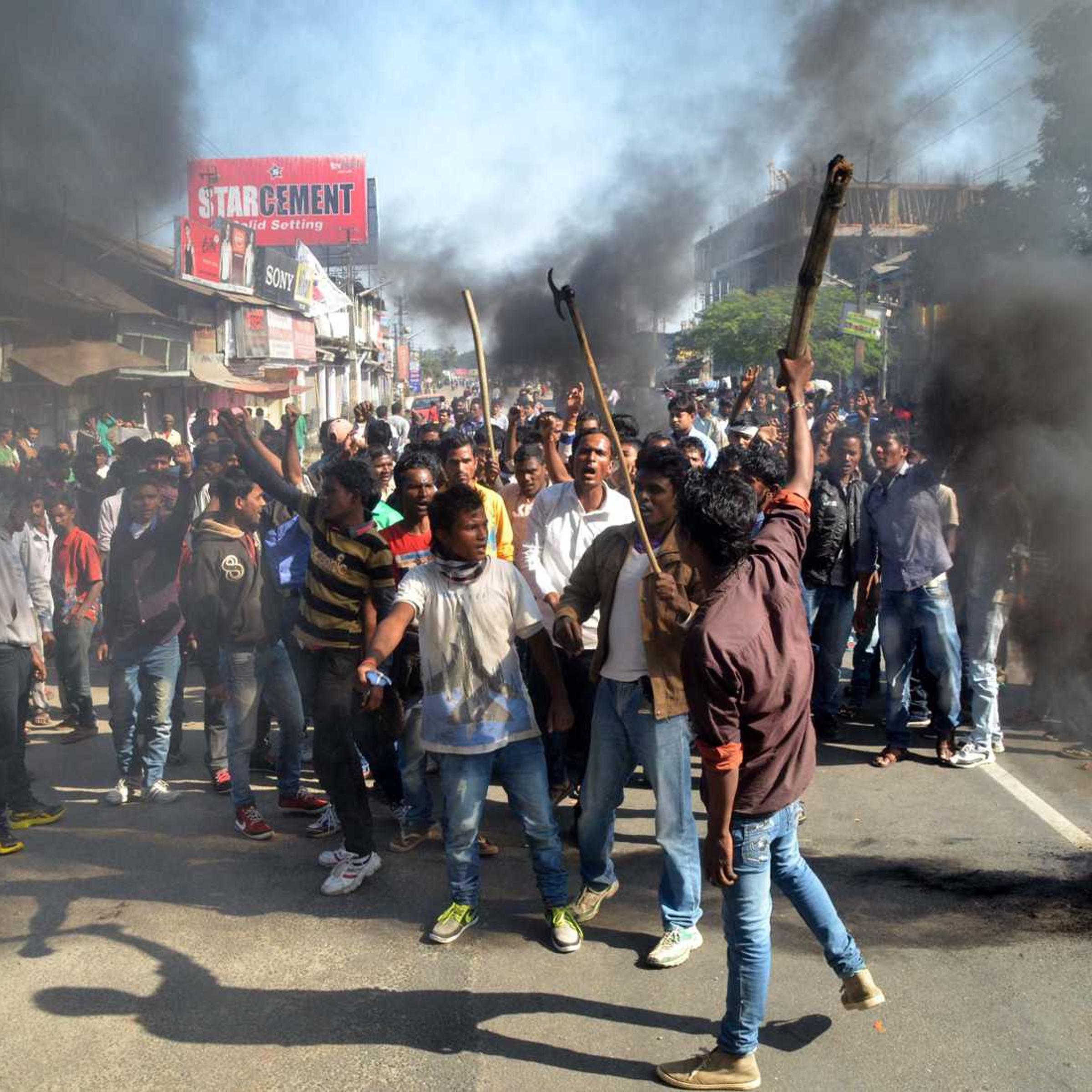 Activists of the Assam Tea Tribes Student Association (ATTSA) shout slogans as they block the road with burning tyres during a protest against attacks on villagers by militants in four different locations, at Biswanath Chariali in the Sonitpur district of northeastern Assam state on December 24, 2014