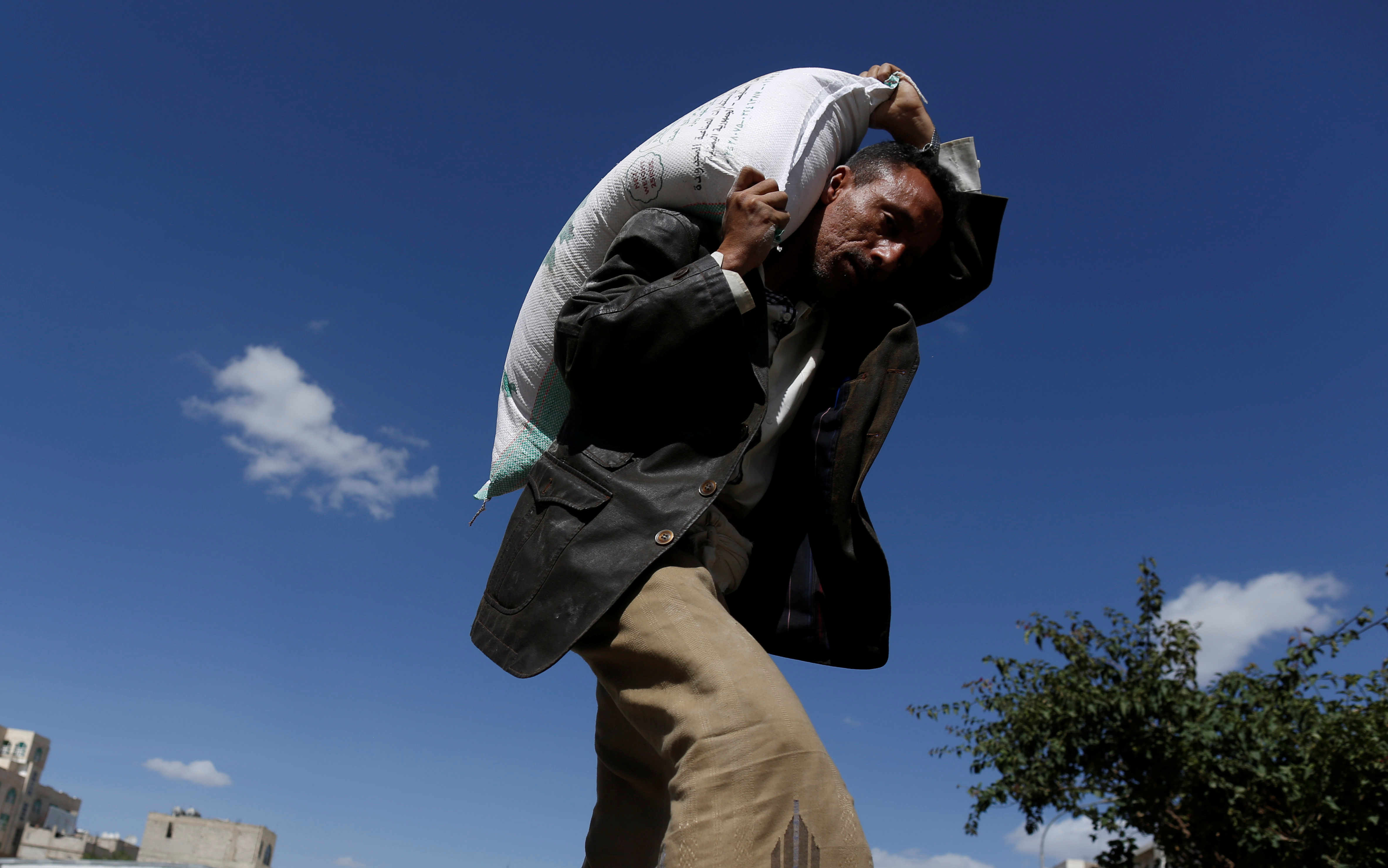 A man carries a sack of wheat flour he received from a local charity during the holy month of Ramadan in Sanaa