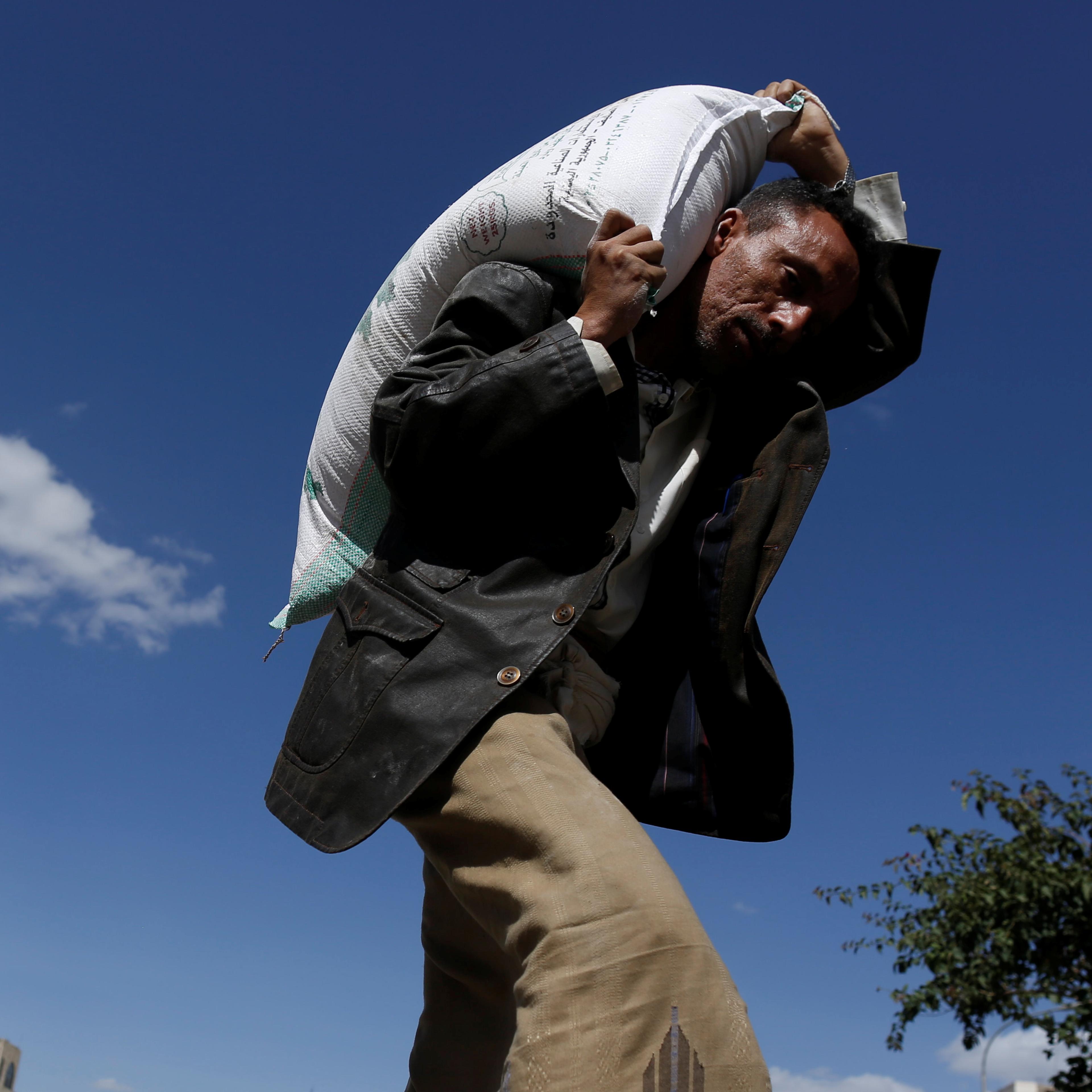 A man carries a sack of wheat flour he received from a local charity during the holy month of Ramadan in Sanaa