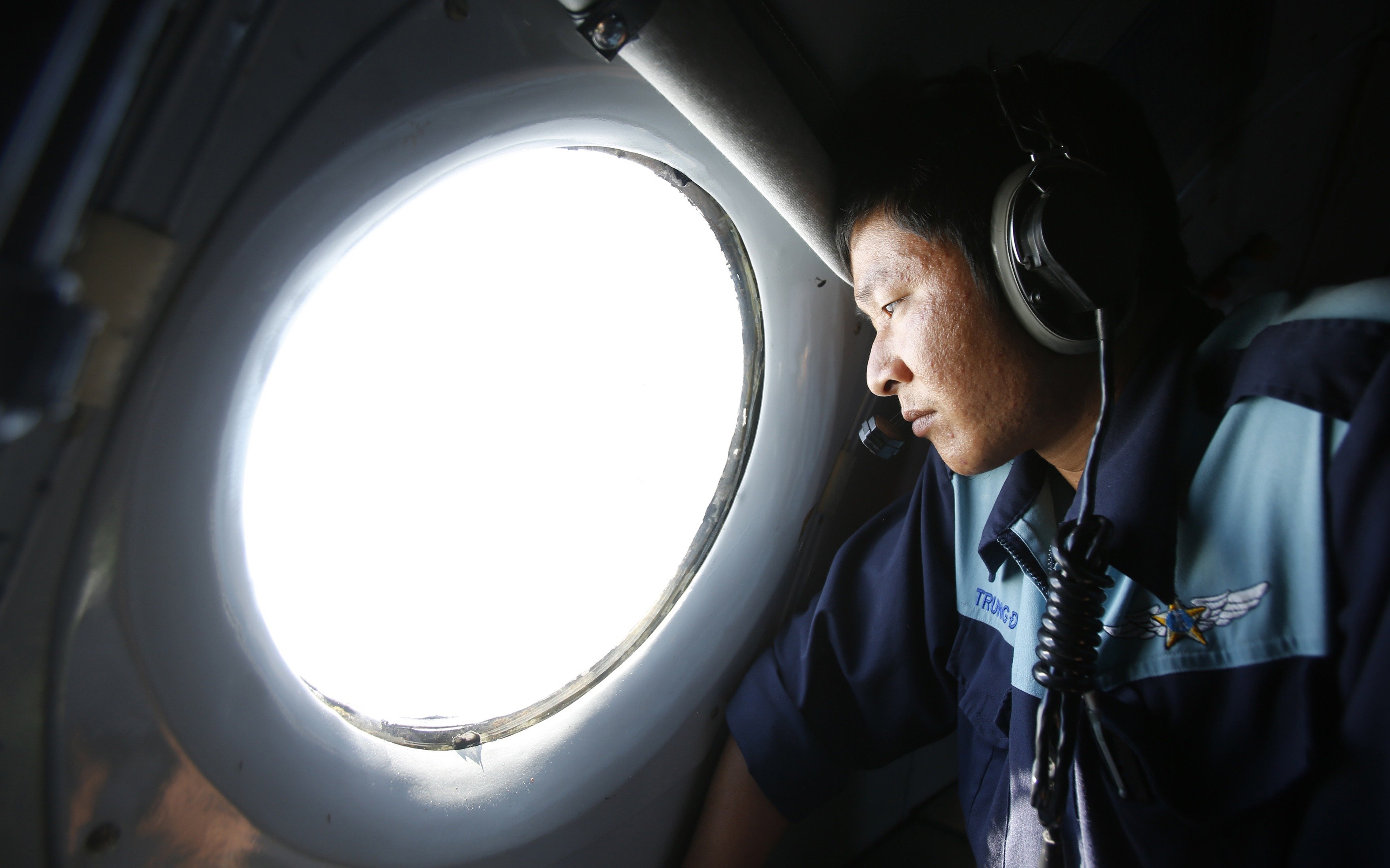 Military officer Nguyen Tran looks out from a Vietnam Air Force AN-26 aircraft during a mission to find the missing Malaysia Airlines flight MH370, off Con Dao island, on March 14, 2014.
