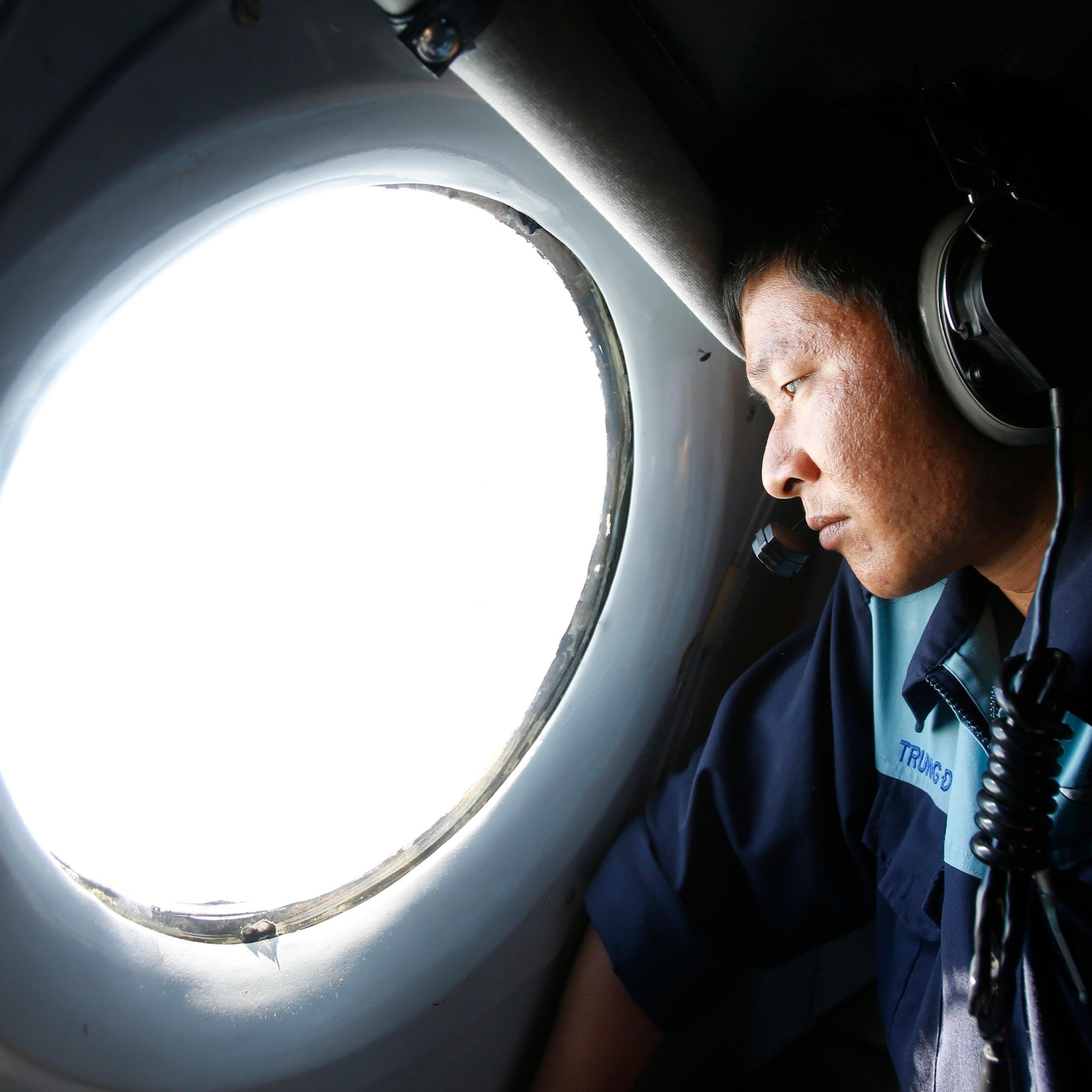 Military officer Nguyen Tran looks out from a Vietnam Air Force AN-26 aircraft during a mission to find the missing Malaysia Airlines flight MH370, off Con Dao island, on March 14, 2014.