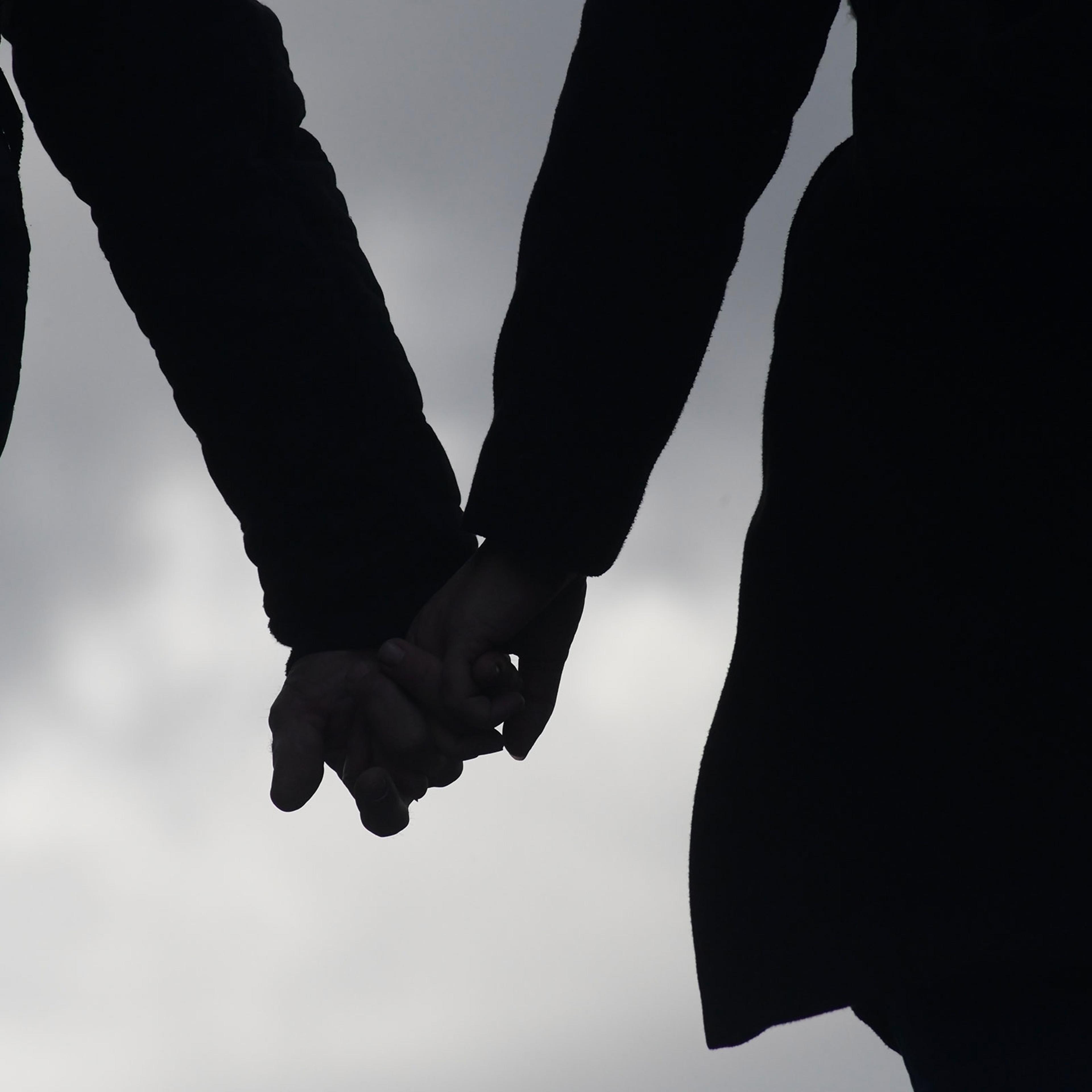 A silhouette of two people holding hands