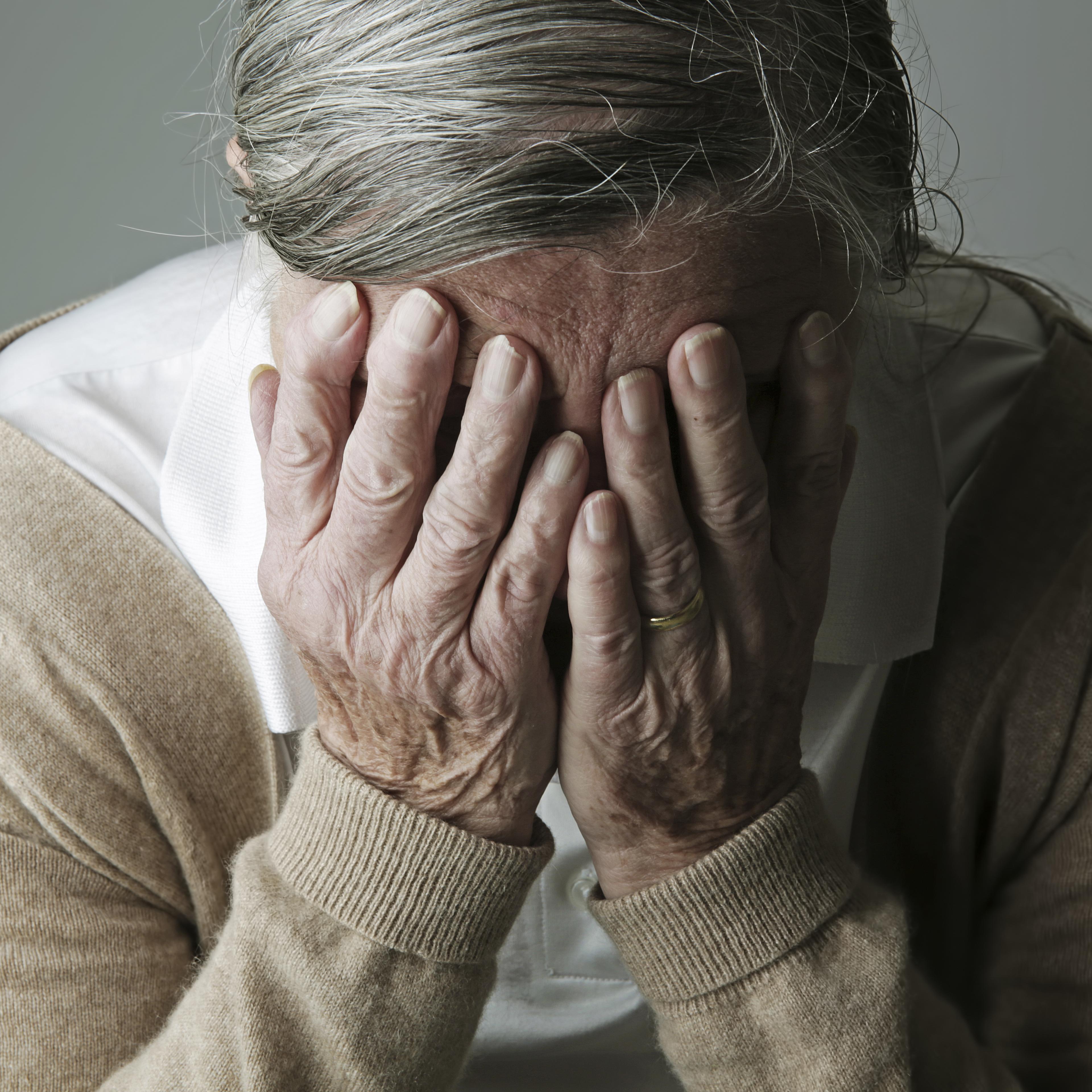 Senior woman covering face with her hands