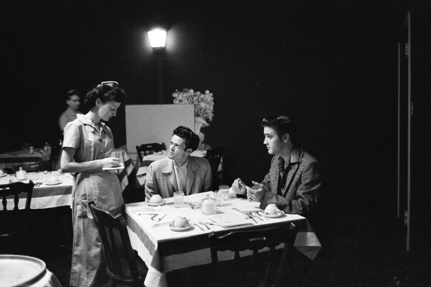 June 30, 1956. The main dining room at the Jefferson Hotel in Richmond, Virginia. Elvis with his cousin 'Junior' Smith. Junior is thinking about food and Elvis is looking at the girl. 15 minutes later, he’s got his arm around her waist and she’s grinning from ear to ear. Elvis ordered two eggs sunny side down, french fries and bacon. For desert, half a cantaloupe and vanilla ice cream.