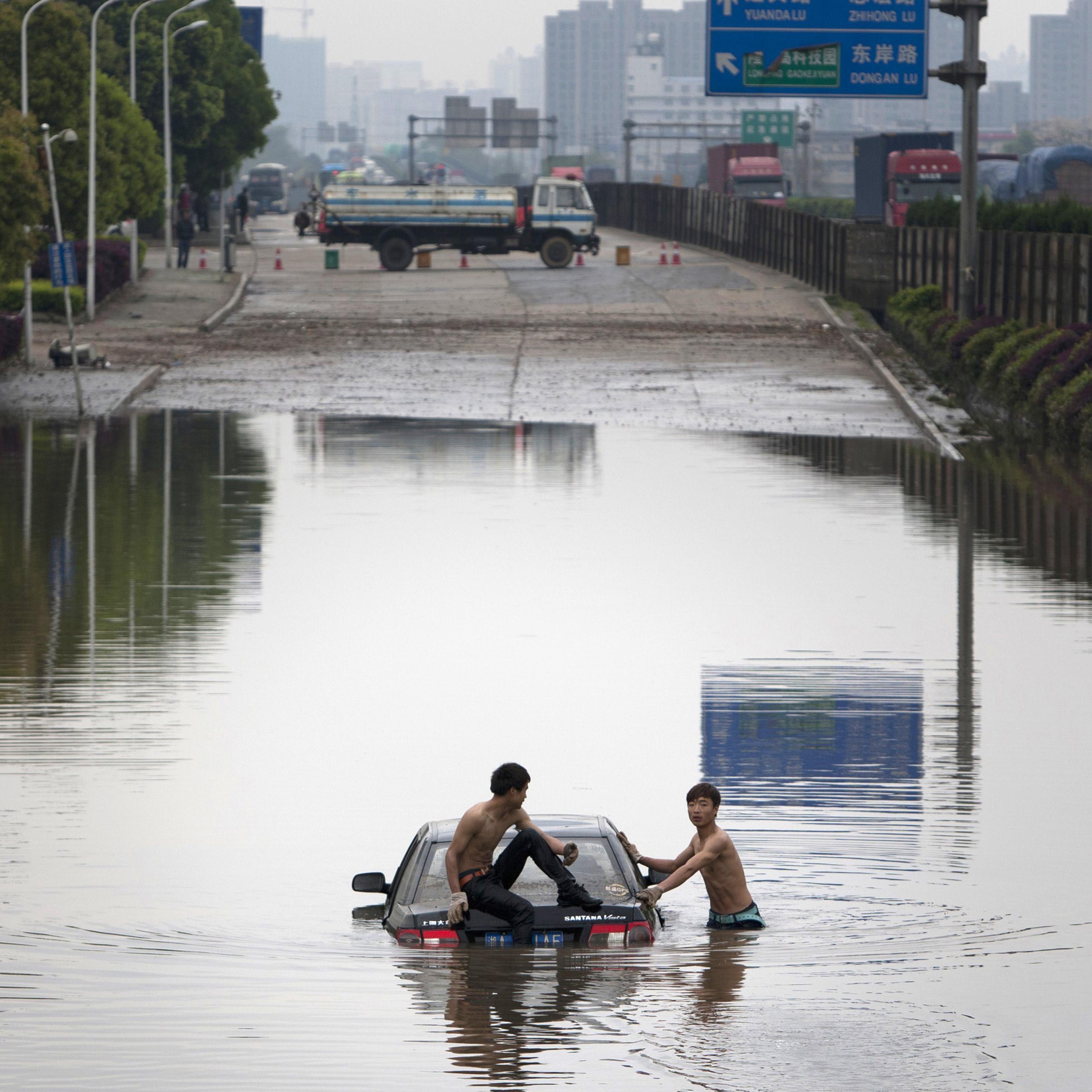 This picture shows two men attempting to push a car out of floodwaters after a storm swept Changsha, central China's Hunan province on taken on April 7, 2015