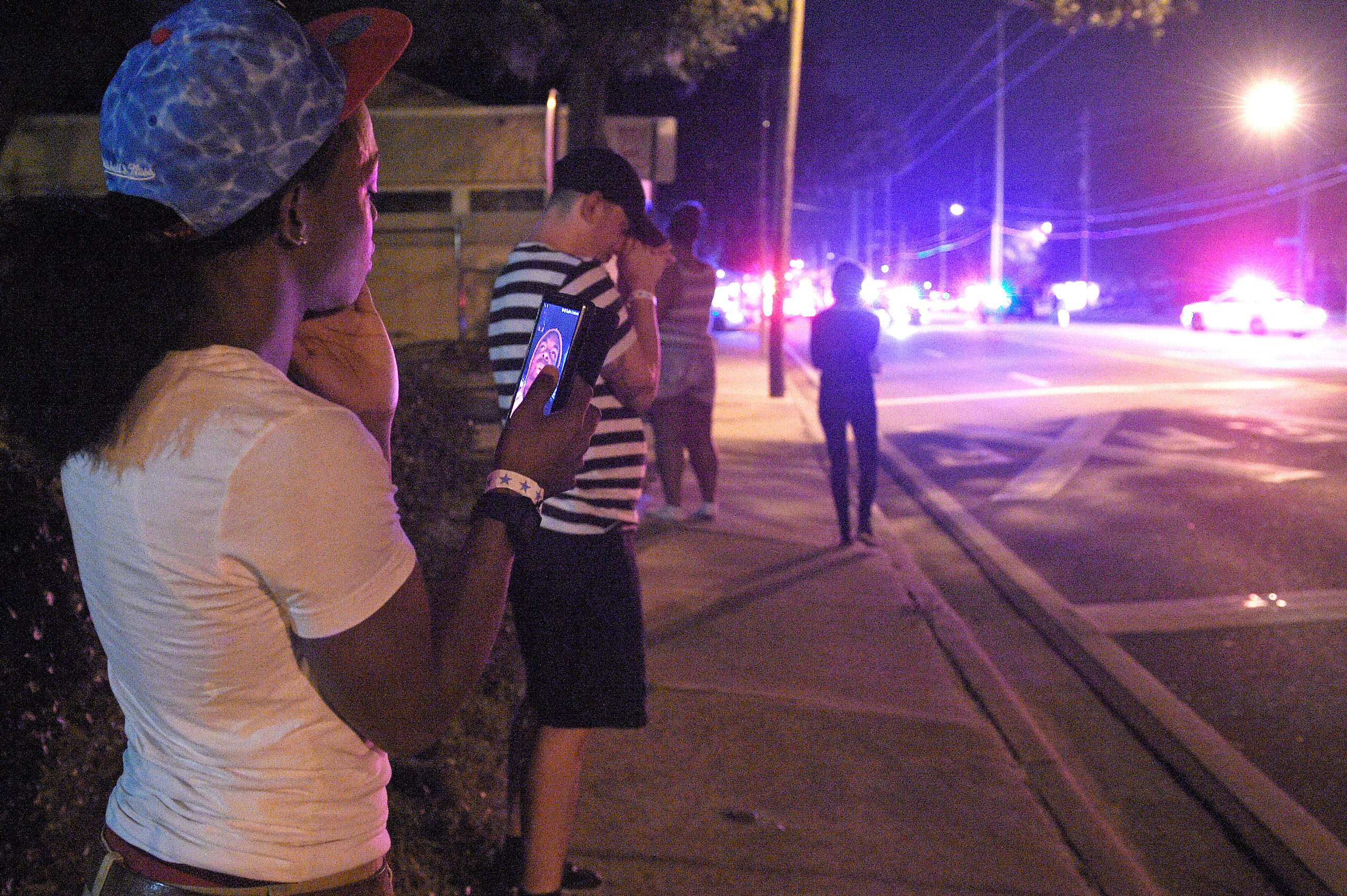 Jermaine Towns, left, and Brandon Shuford, second from left, wait down the street from the scene of a shooting involving multiple fatalities at a nightclub in Orlando, Fla., Sunday, June 12, 2016. Towns said his brother was hiding in a bathroom at the ti