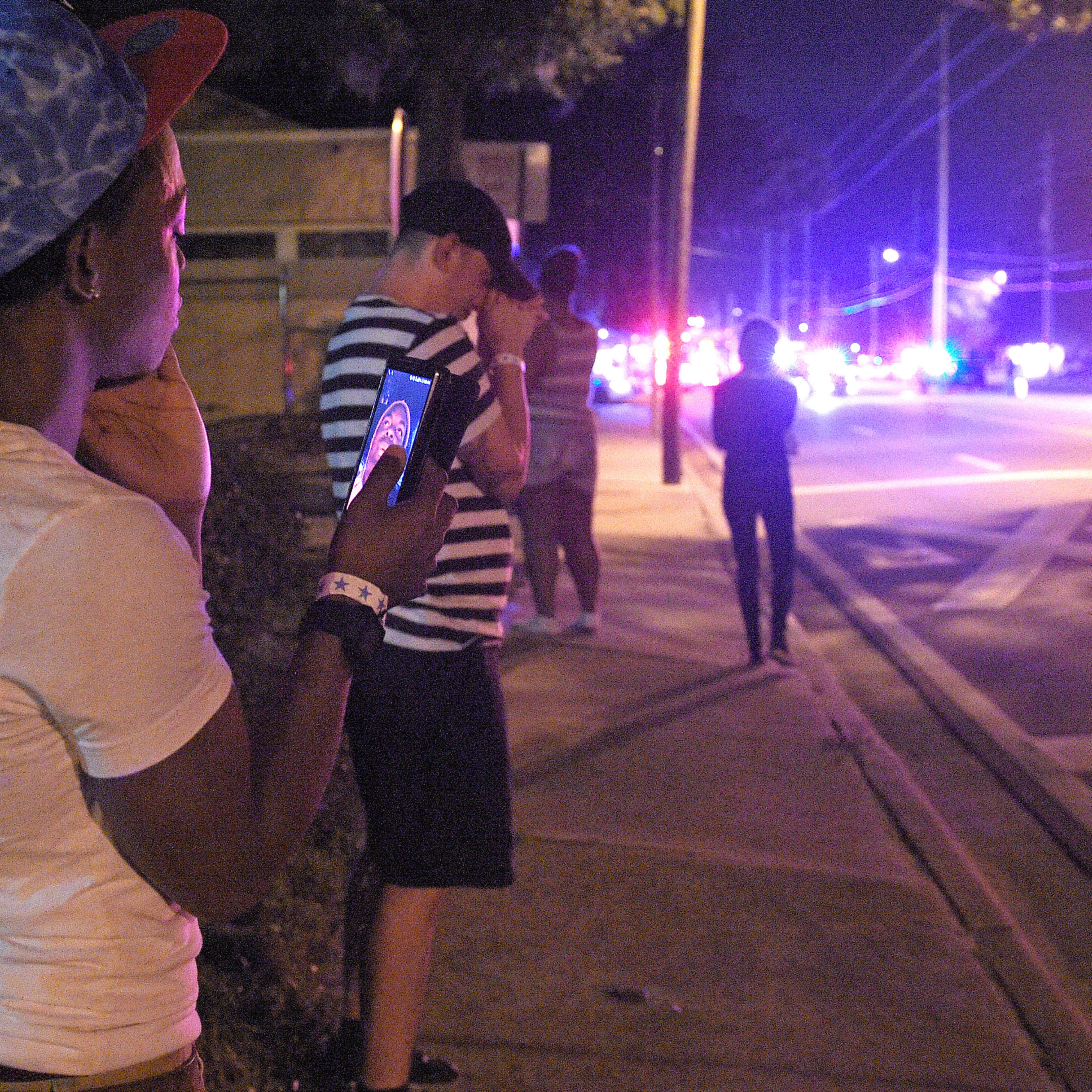 Jermaine Towns, left, and Brandon Shuford, second from left, wait down the street from the scene of a shooting involving multiple fatalities at a nightclub in Orlando, Fla., Sunday, June 12, 2016. Towns said his brother was hiding in a bathroom at the ti