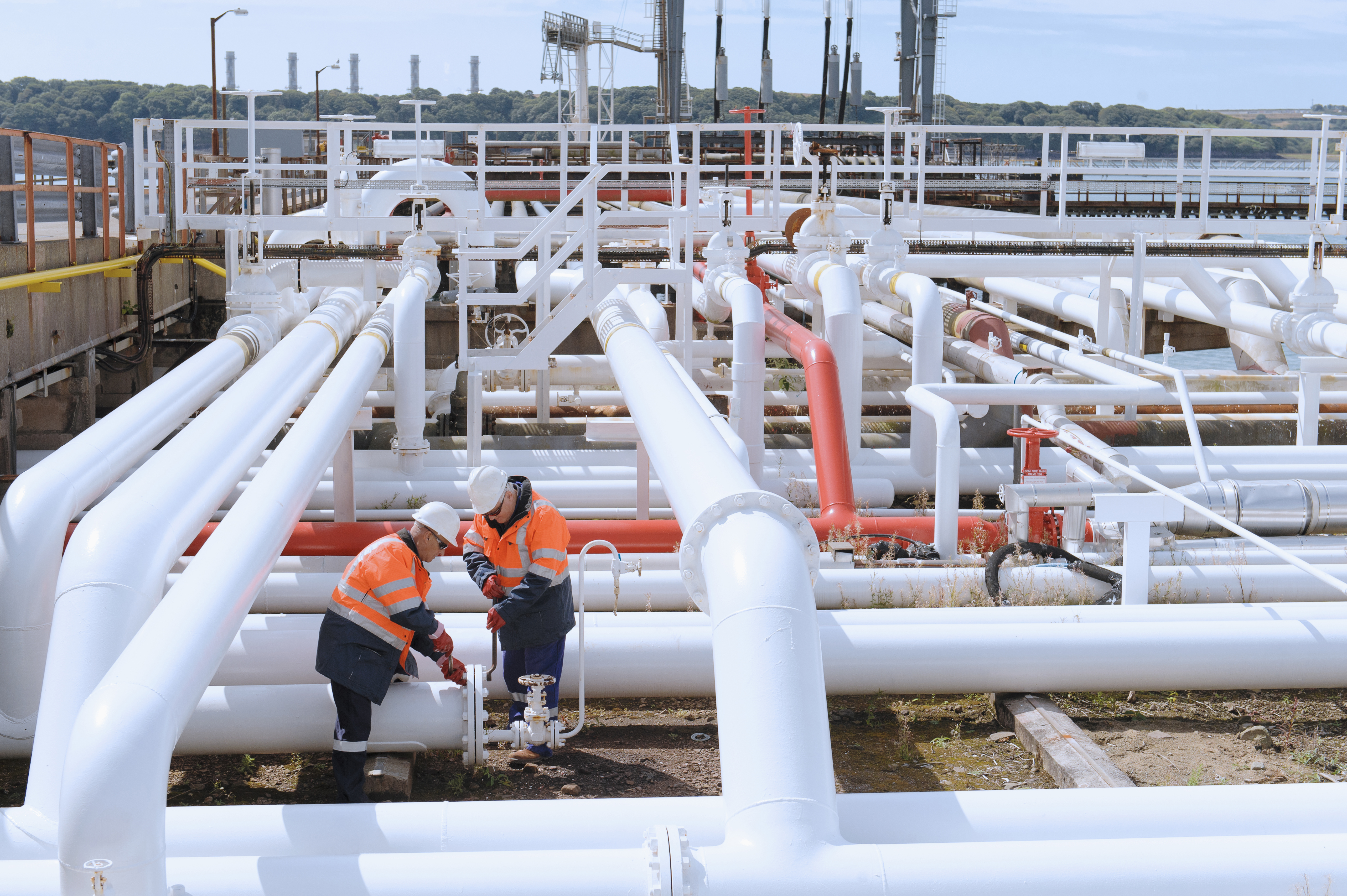 Caucasian technicians tightening bolts on pipe