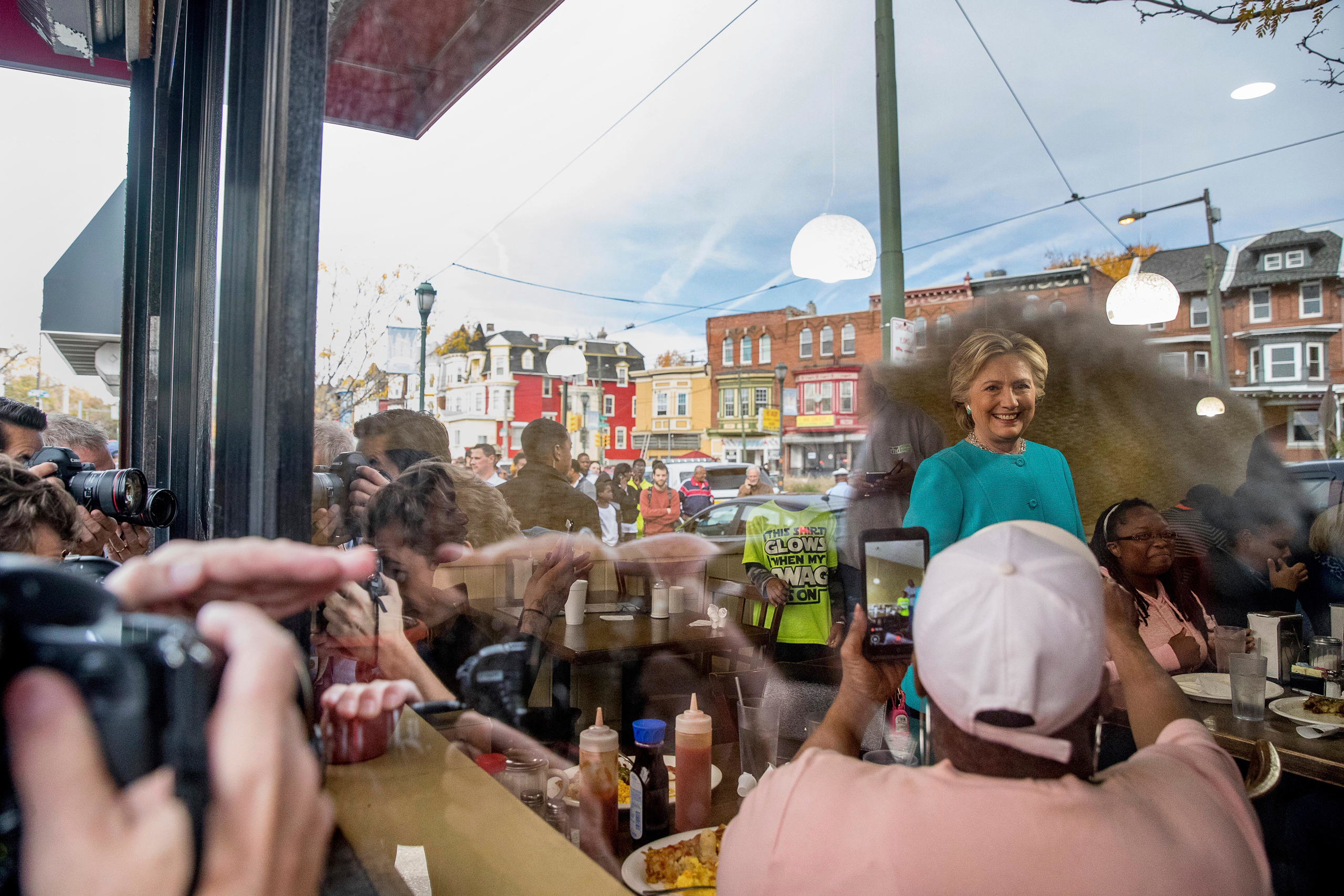 As seen through a window, Democratic presidential candidate Hillary Clinton greets patrons at Cedar Park Cafe in Philadelphia, Sunday, Nov. 6, 2016. (AP Photo/Andrew Harnik)