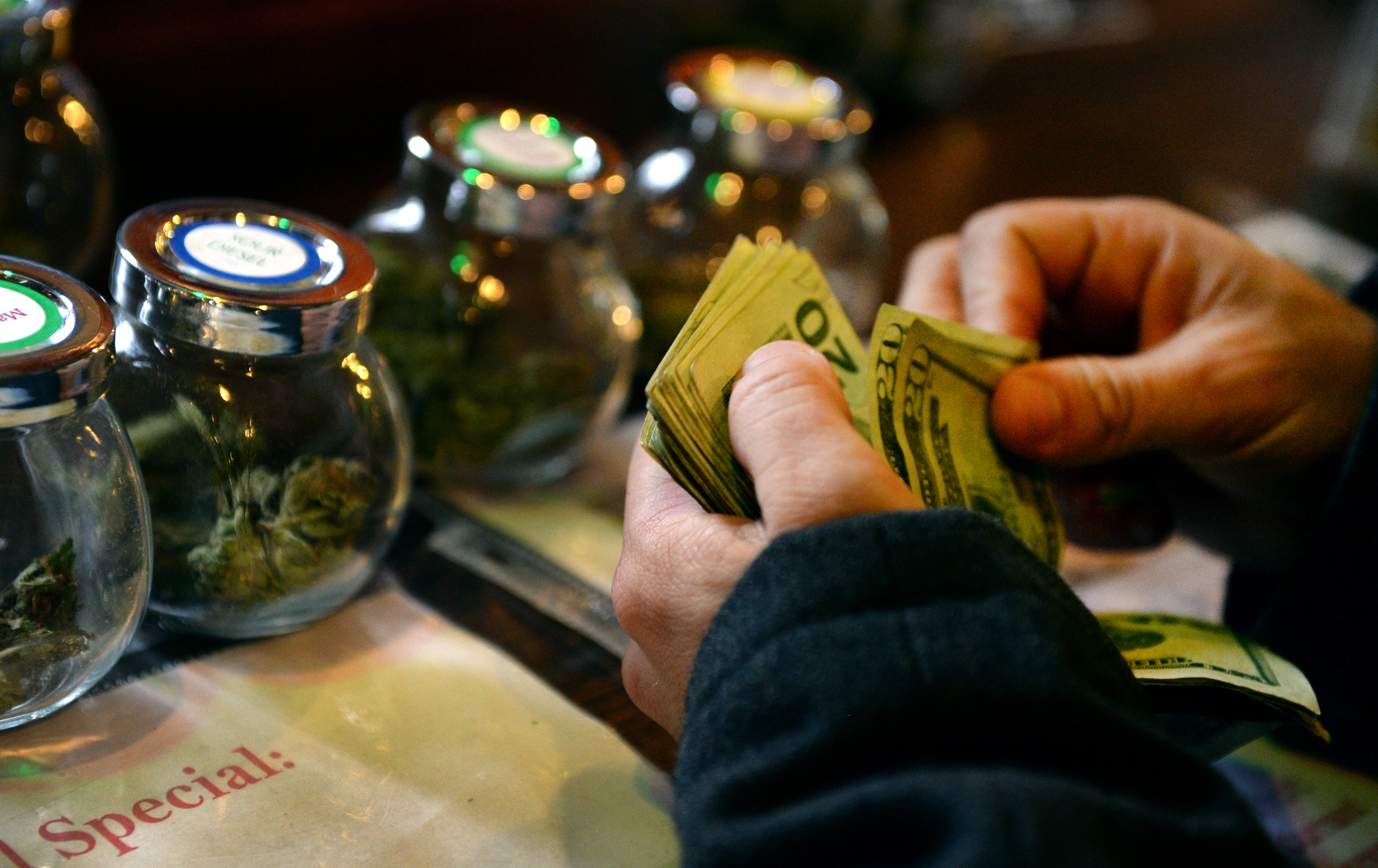 DENVER, CO. - DECEMBER 06: A tour members purchases marijuana at La Conte's Clone Bar &amp; Dispensary during a marijuana tour hosted by My 420 Tours in Denver, CO on December 06, 2014. During the day tourists visited La Conte's grow facility, La Conte's