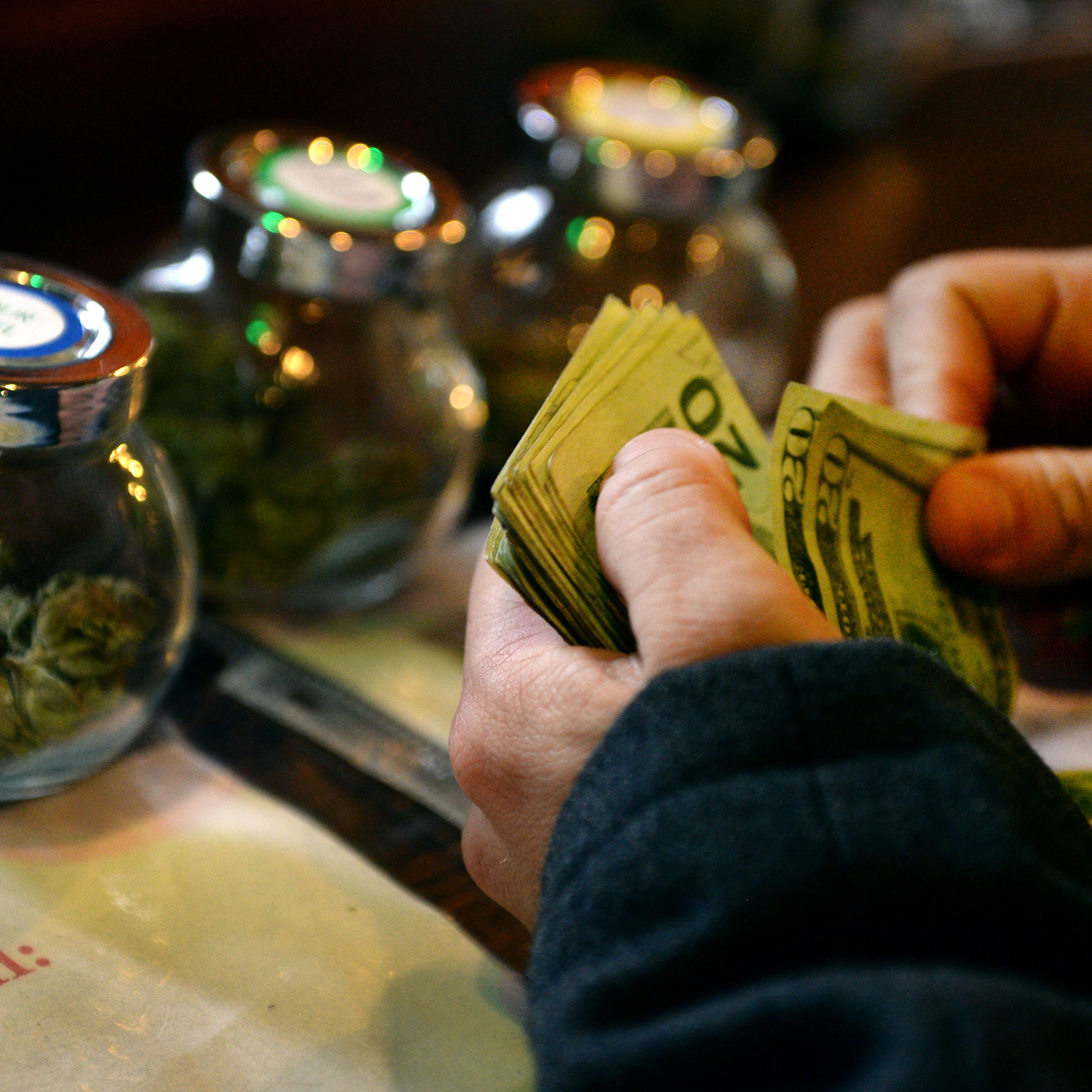 DENVER, CO. - DECEMBER 06: A tour members purchases marijuana at La Conte's Clone Bar & Dispensary during a marijuana tour hosted by My 420 Tours in Denver, CO on December 06, 2014. During the day tourists visited La Conte's grow facility, La Conte's