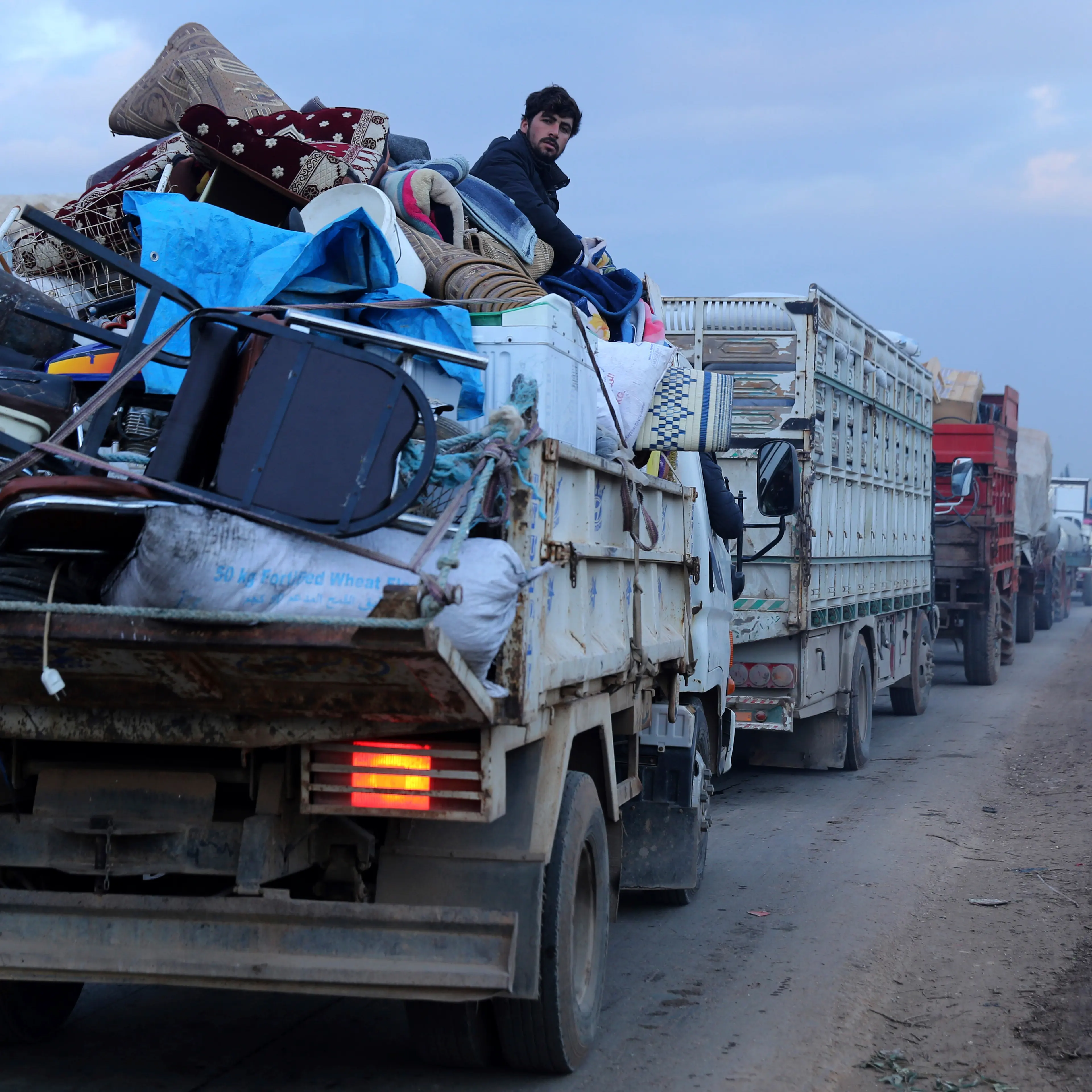 A man rides in a truck as civilians flee