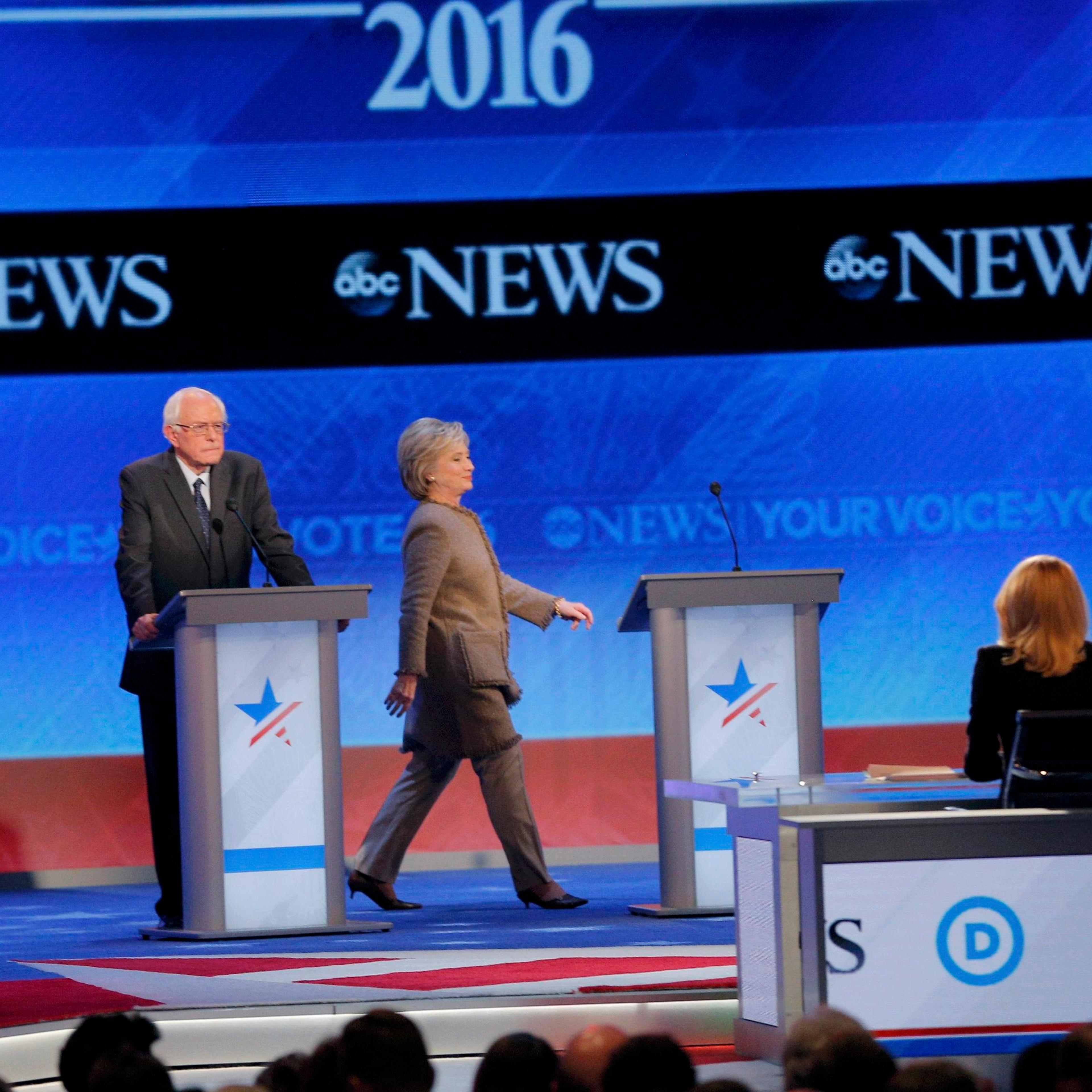 Democratic U.S. presidential candidate Clinton walks to her podium between rivals Sanders and O'Malley after she failed to return from a break in time for the resumption of the Democratic presidential candidates debate at St. Anselm College in Manchester