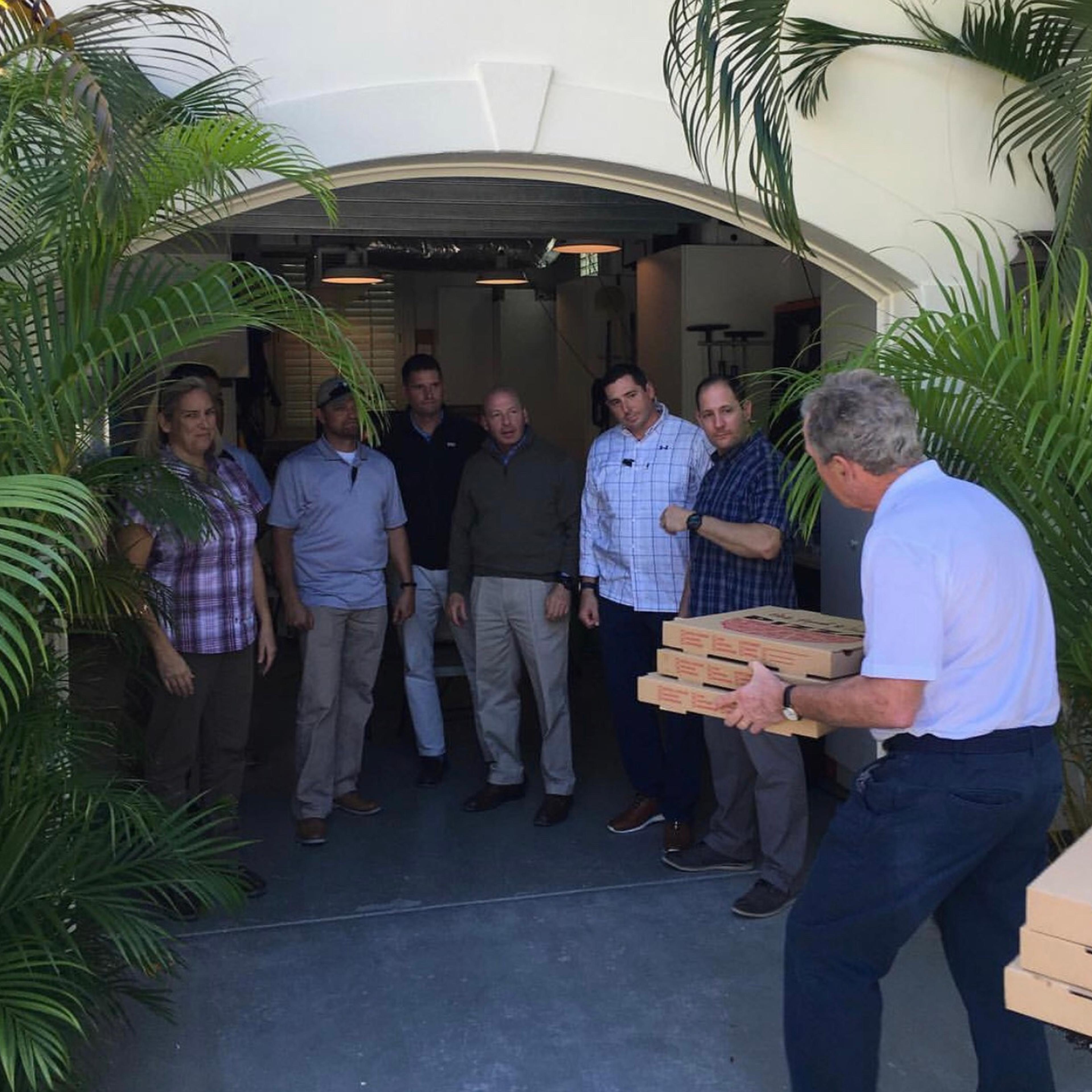 Former president George W. Bush hands pizza to his secret service personnel.