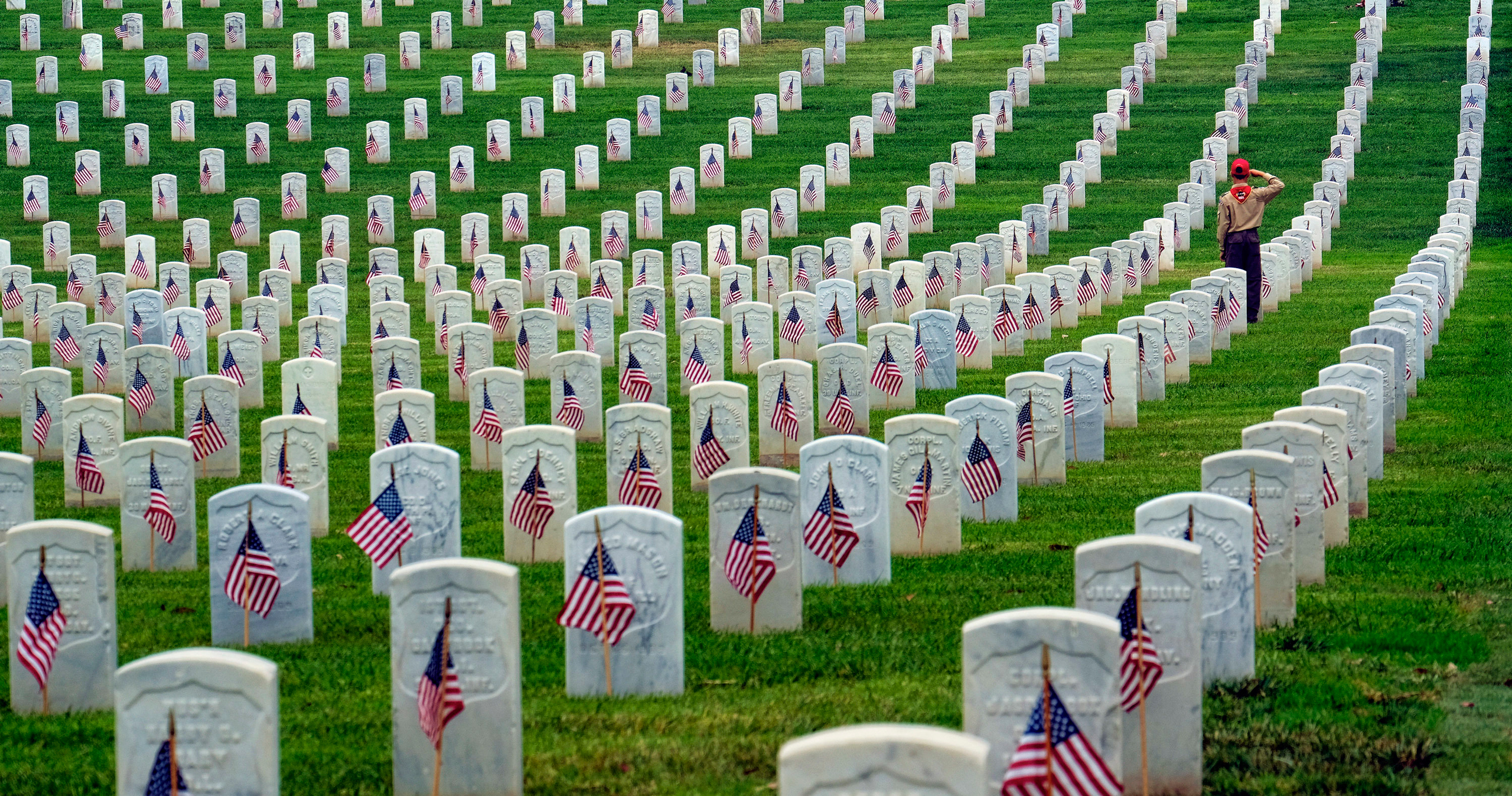 A Boy Scout salutes at the foot of a grave after volunteers placed flags at the Los Angeles National Cemetery on Saturday, May 28, 2016 in preparation for Memorial Day. (AP Photo/Richard Vogel