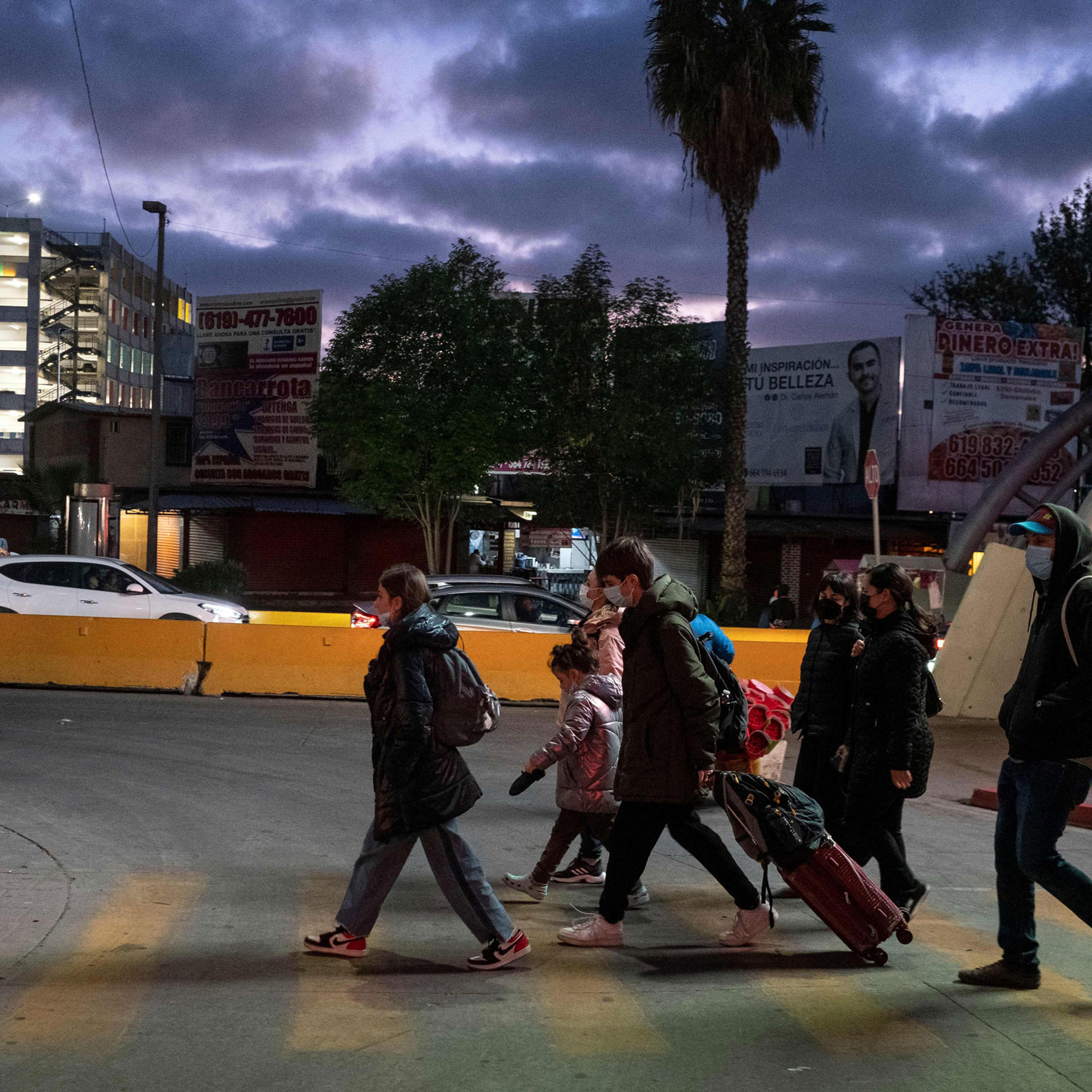 Ukrainian citizens walk along with advocates on the Mexican side of the border